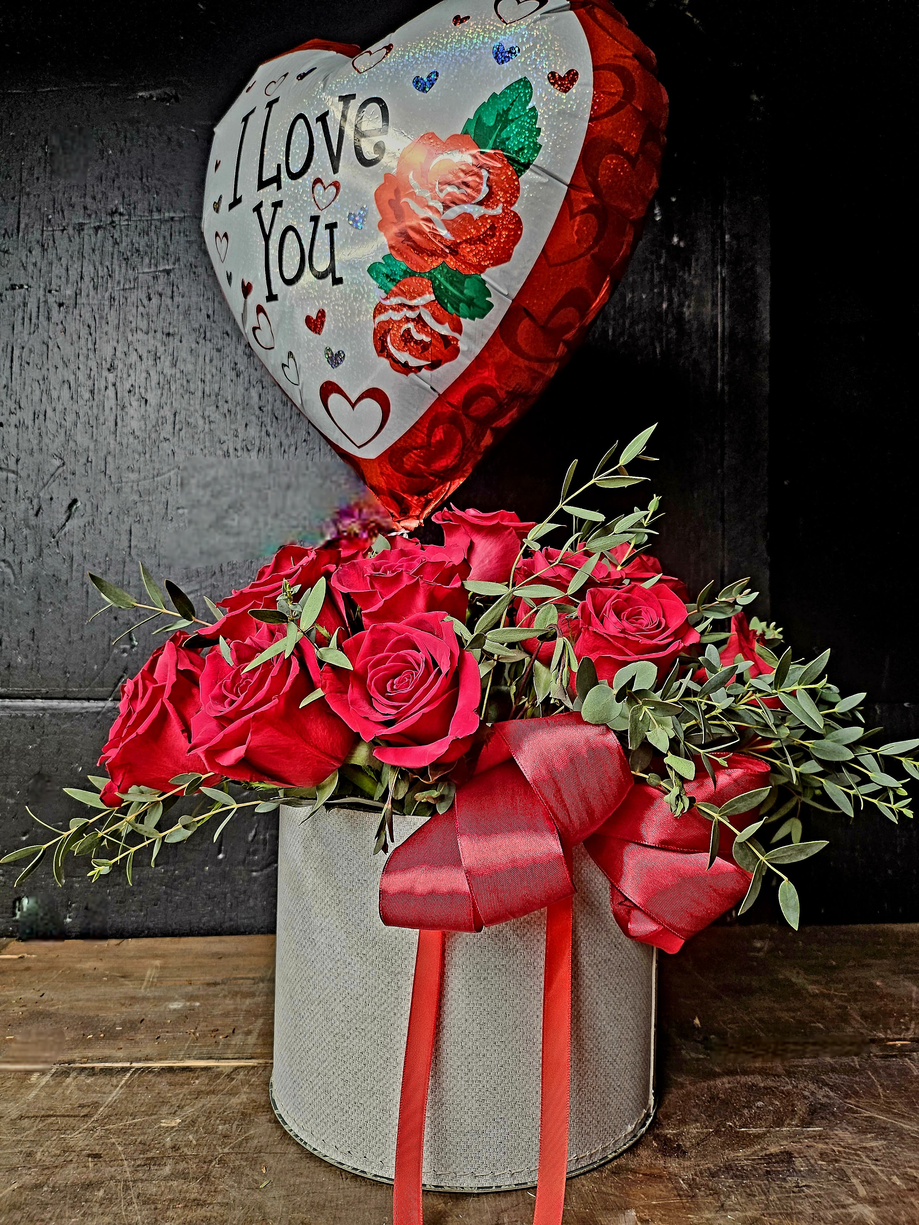 Red rose arrangement in a gray box with a heart-shaped "I Love You" balloon