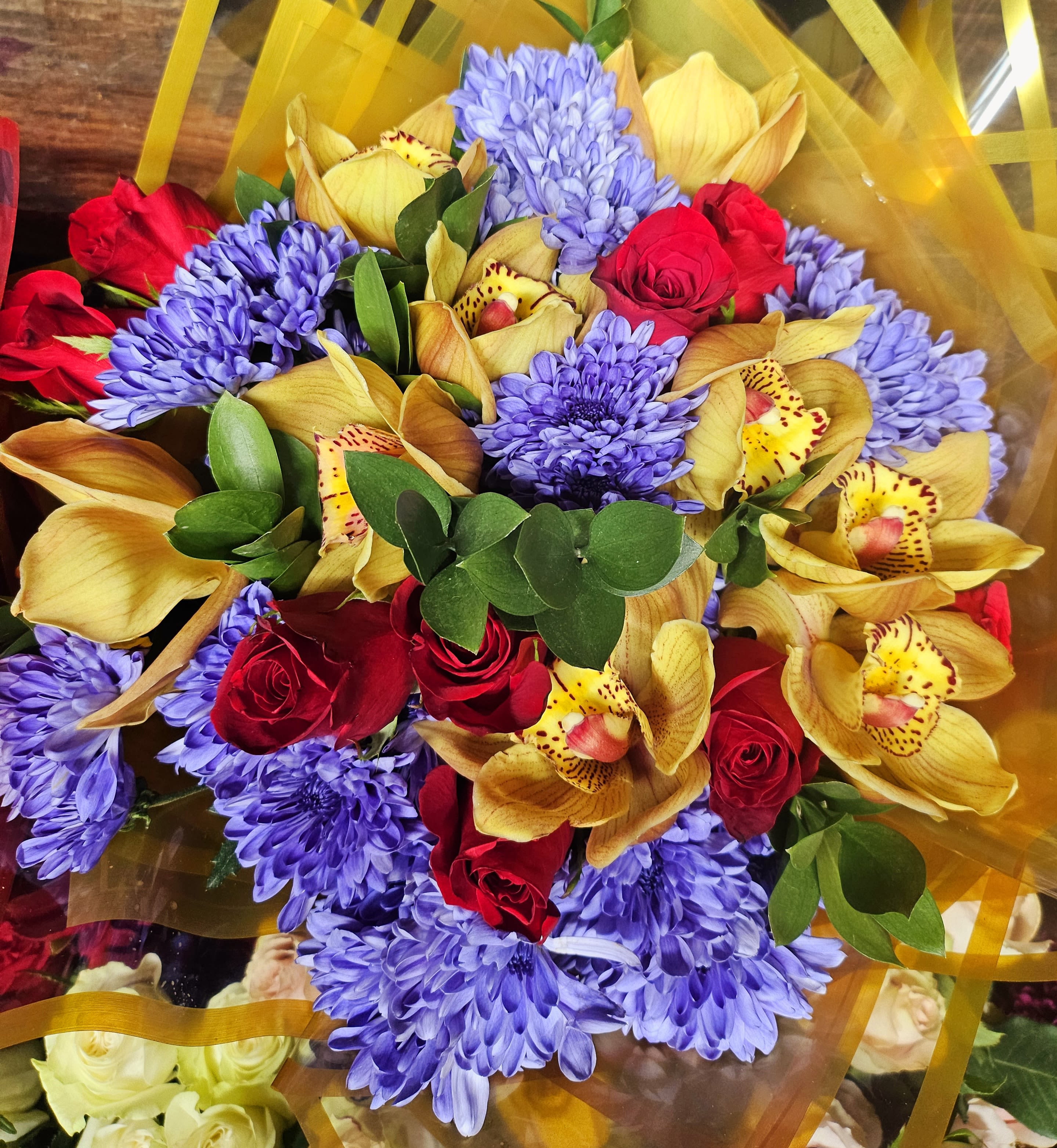 Bouquet of red roses, purple chrysanthemums, and yellow orchids