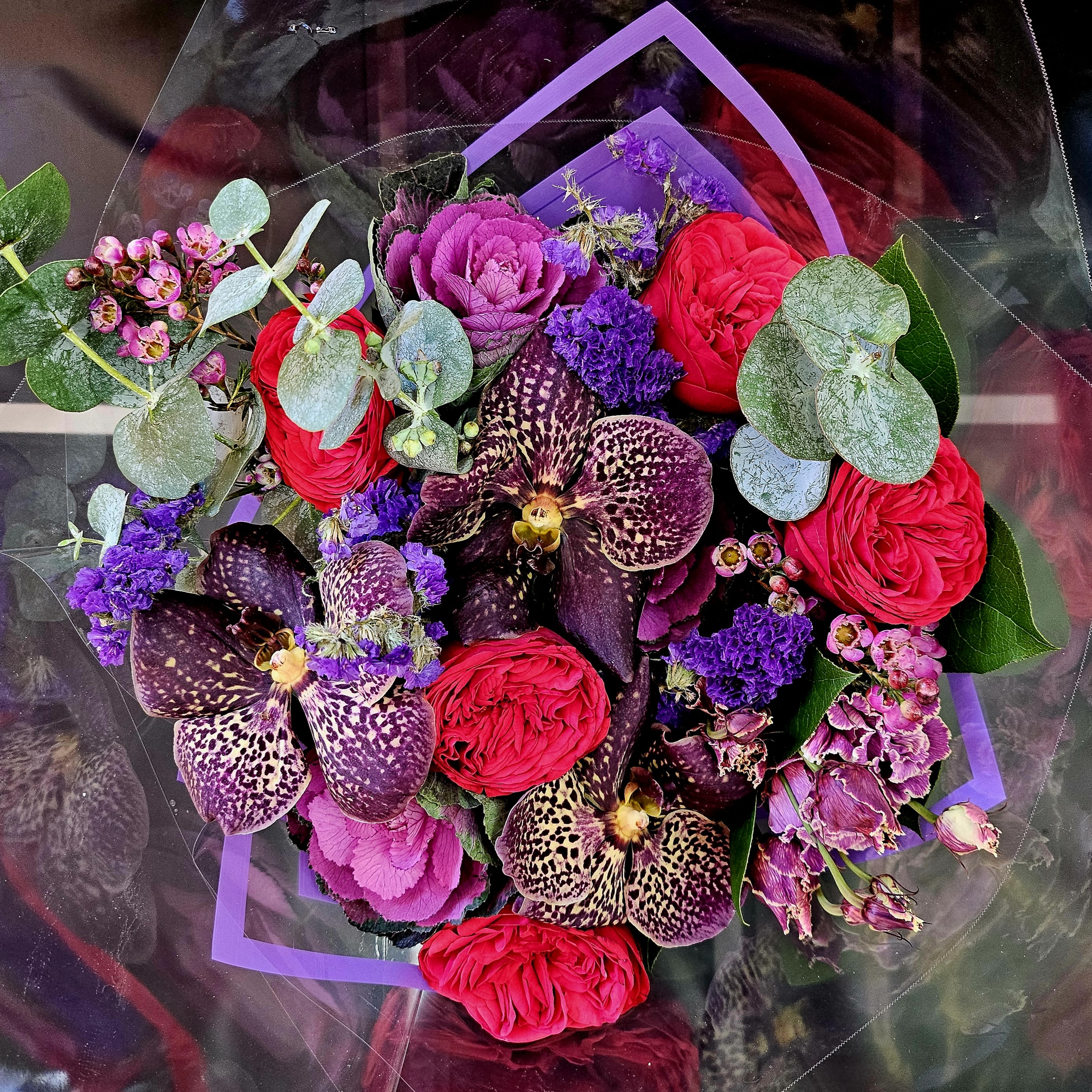 Bouquet of red roses, purple orchids, and pink cabbage roses