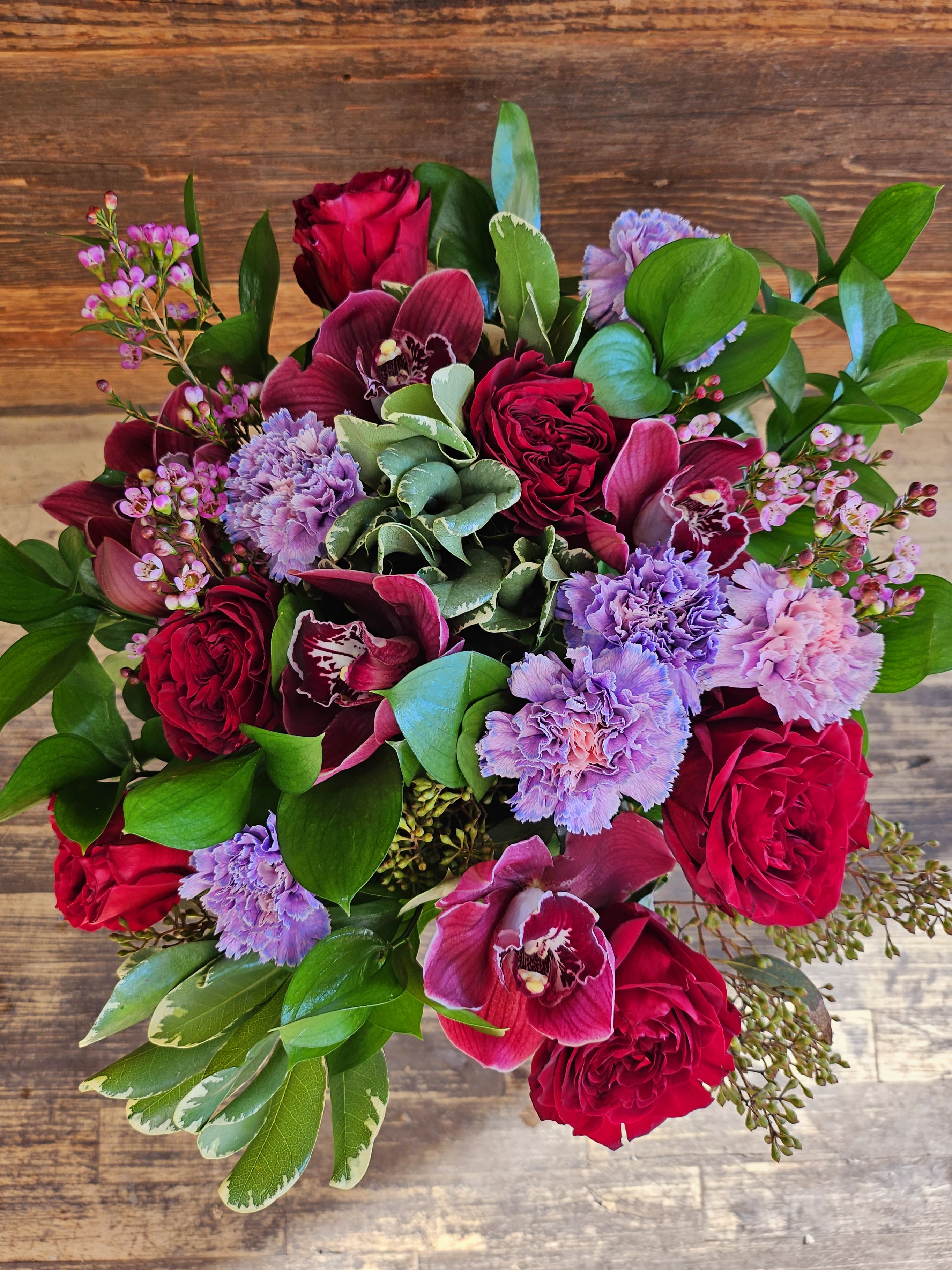 Bouquet of red roses, purple orchids, and lavender carnations