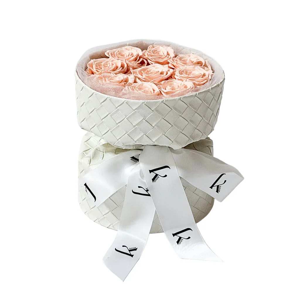 Peach roses in a white woven hatbox with a ribbon bow