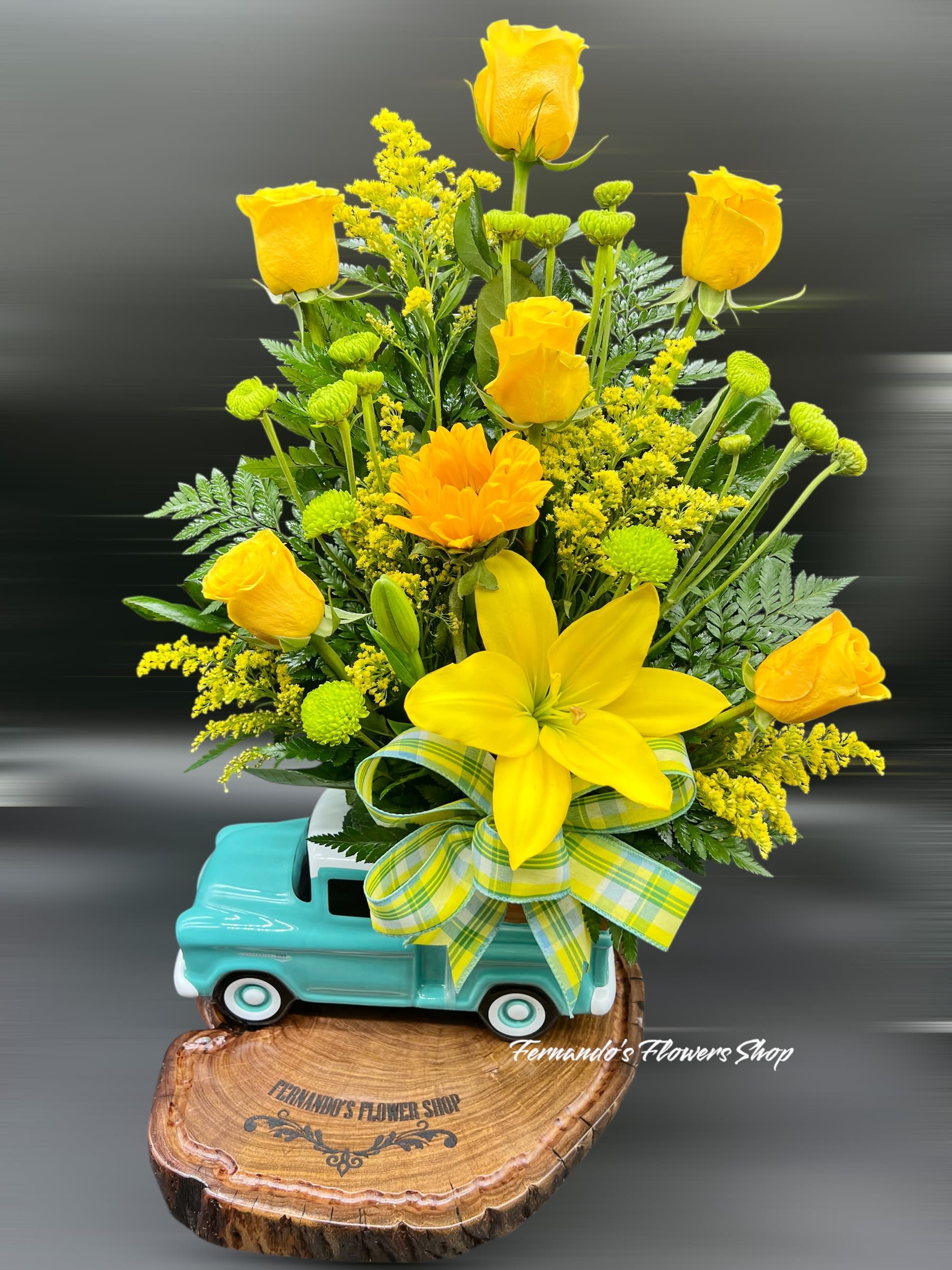 Yellow roses and a lily arranged in a turquoise truck planter