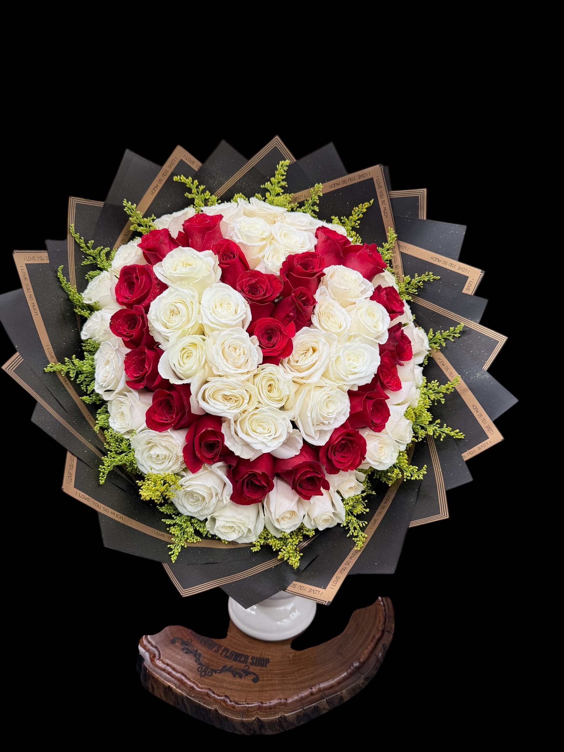 Heart-shaped bouquet of red and white roses in black wrap