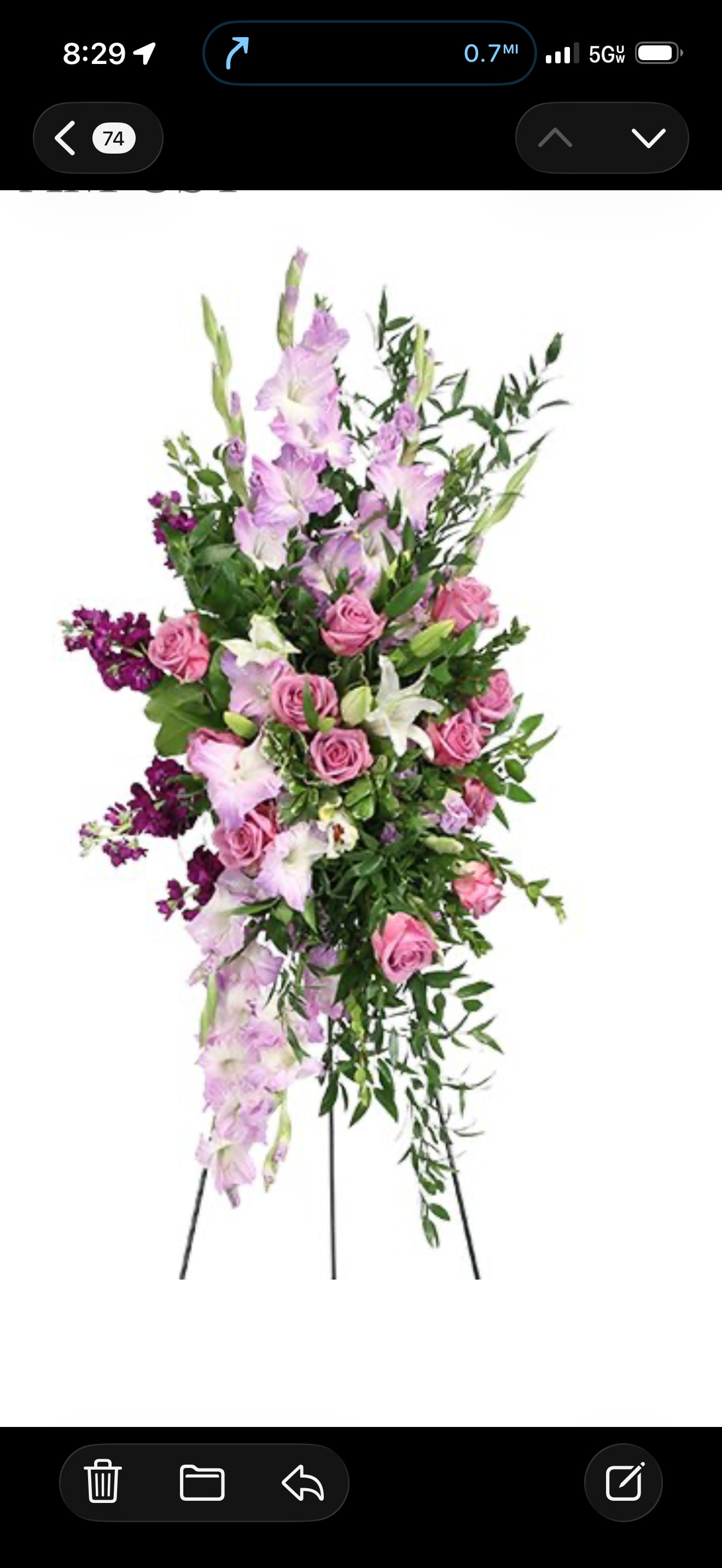 Sentimental Song - Lavender Grace Standing Spray  Celebrate a beautiful life with this graceful standing spray featuring soft pink roses, elegant lavender gladiolus, fragrant lilies, and rich purple stock, accented with lush cascading greenery. Designed on an easel, this serene arrangement expresses love, comfort, and heartfelt remembrance, offering a meaningful tribute to honor a cherished loved one with beauty and grace.