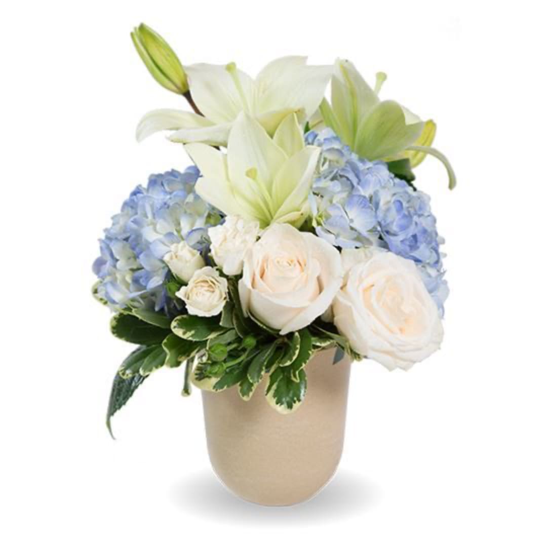 White lilies, blue hydrangeas, and cream roses in a beige vase