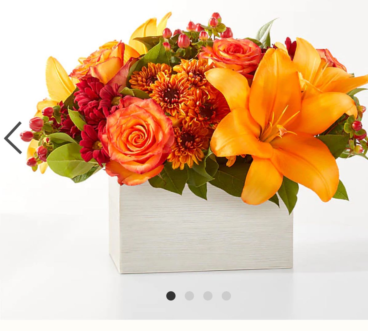 Orange and red floral arrangement in a square white box