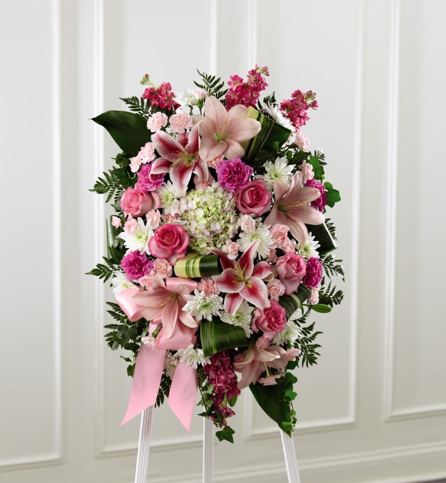 Pink and white floral standing spray on an easel with a ribbon