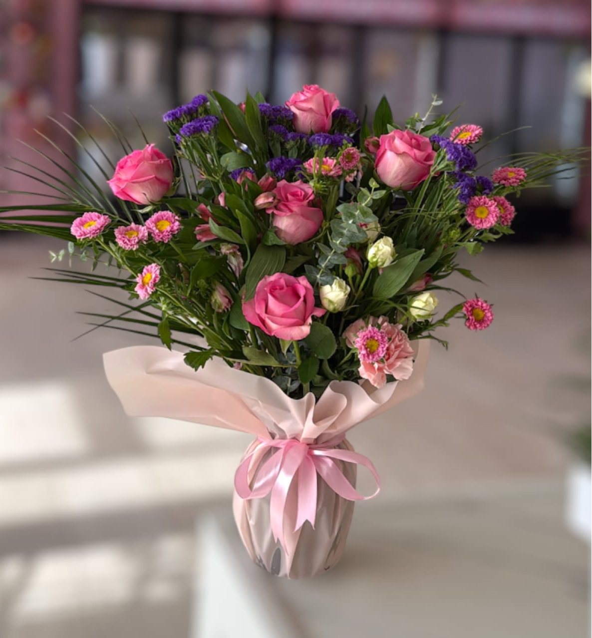 Pink roses and small mixed flowers in a wrapped vase arrangement