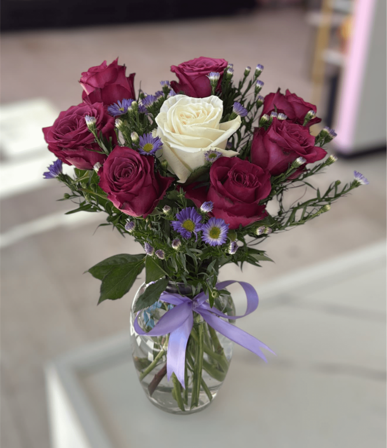 Purple Rose Delight - A stunning purple roses arrangement showcasing purple roses with one white rose. Please note that florists may need to make substitutions based on inventory to ensure the freshest blooms are delivered, while maintaining the arrangement's overall aesthetic.