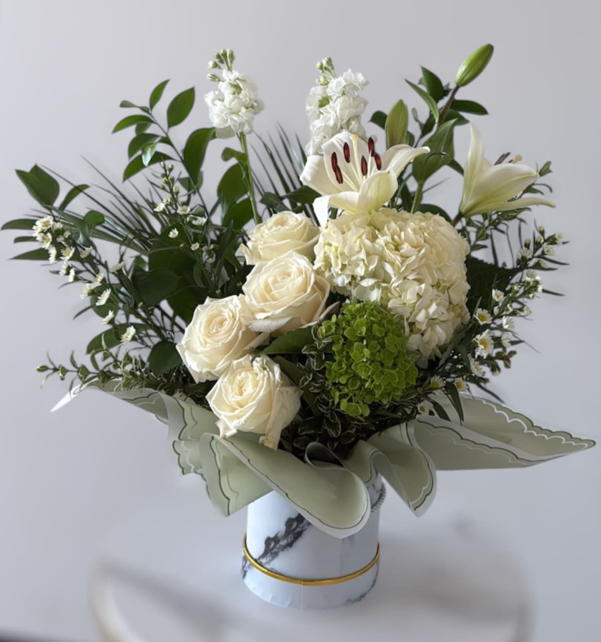 White roses, lilies, and hydrangea in a decorative vase