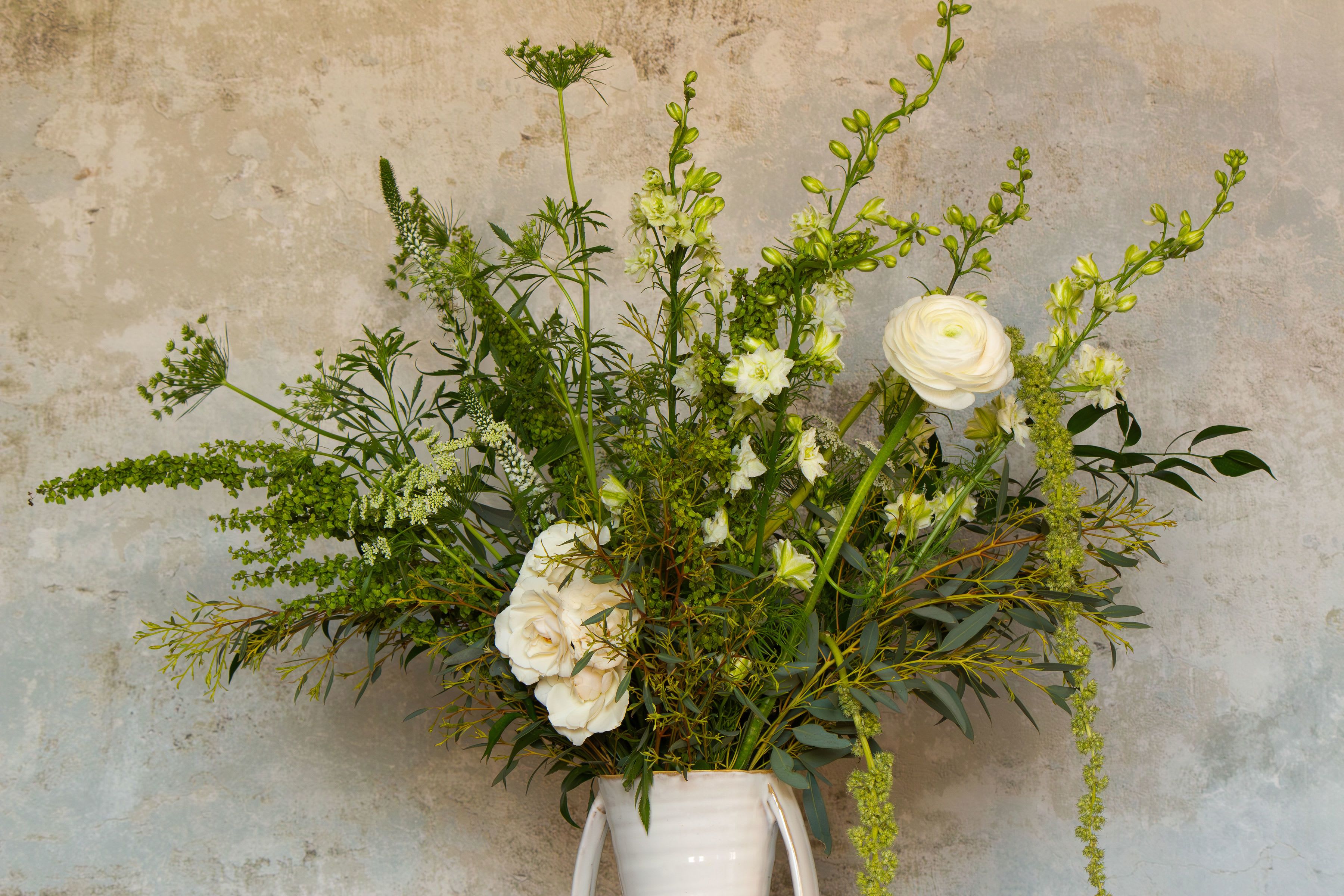 Tall white floral arrangement in a white vase