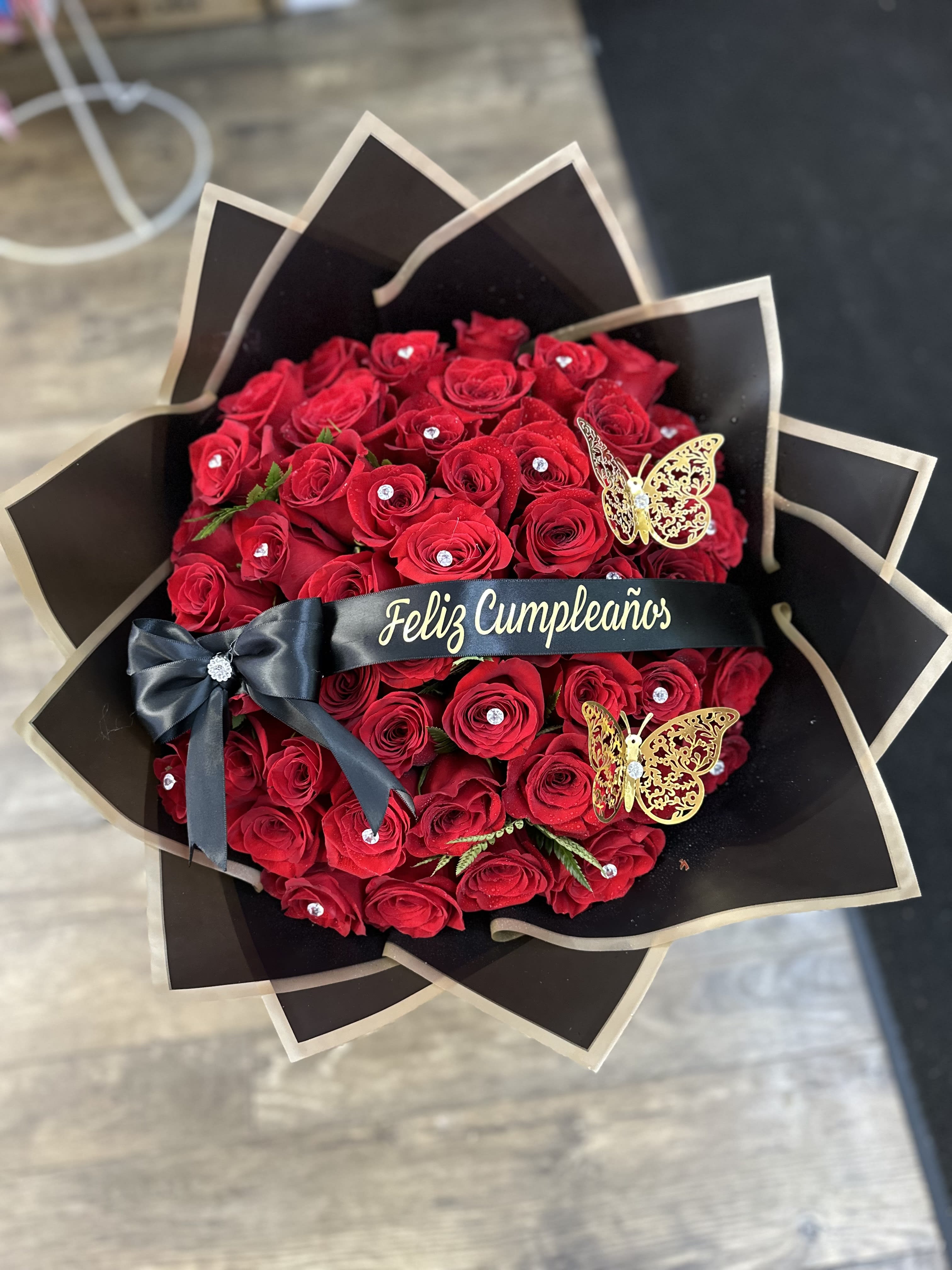 Bouquet of red roses wrapped in black paper with a birthday ribbon