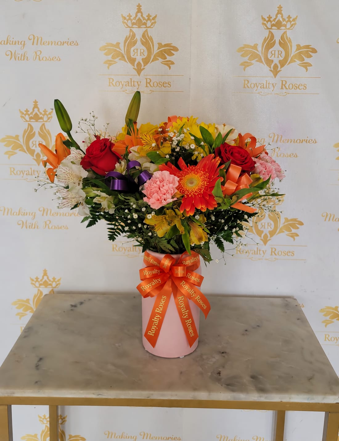 Mixed bouquet of roses, lilies, and gerbera daisies in a pink vase