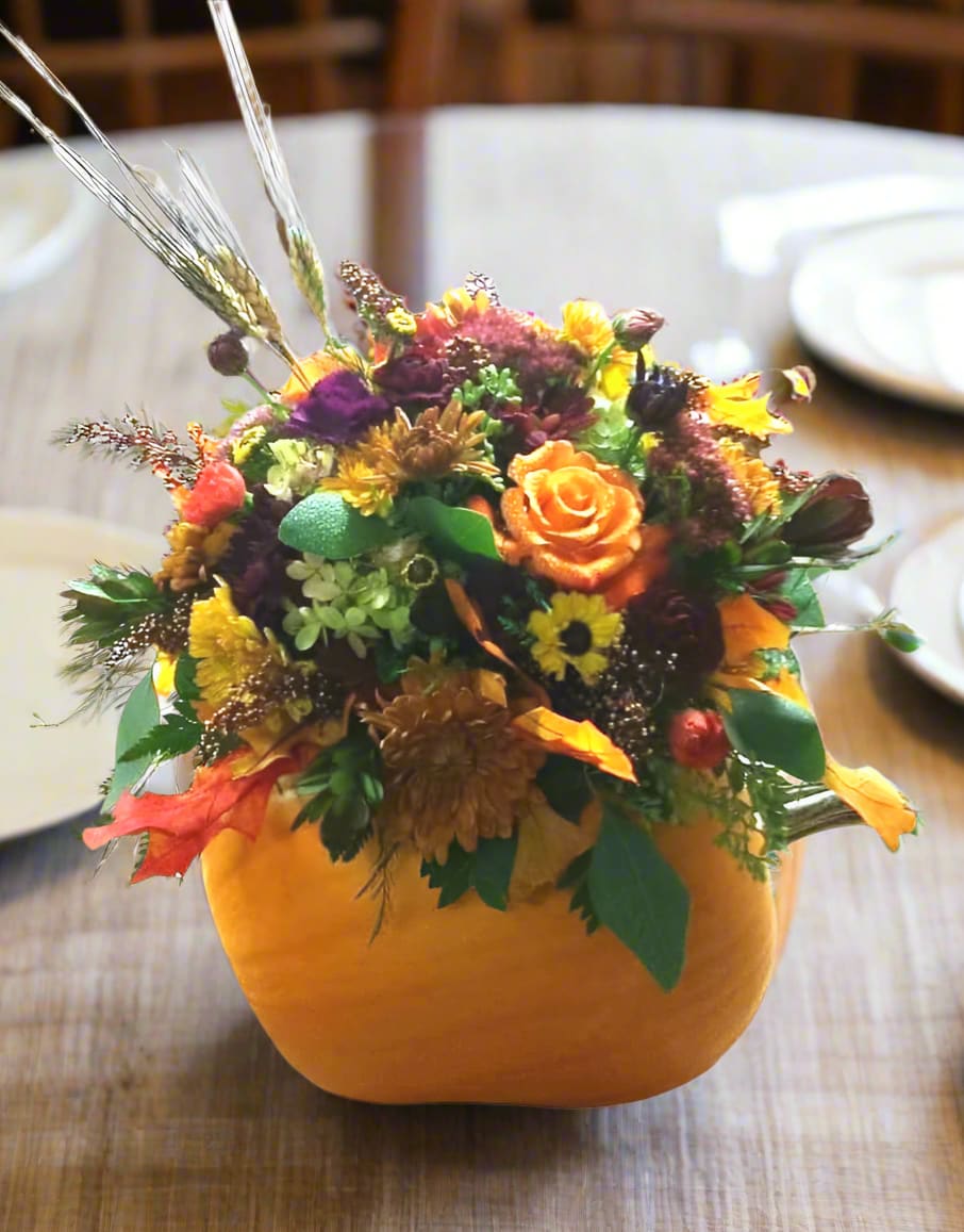 Pumpkin Patch Posies - Elevate your autumn gatherings with our Pumpkin Patch Posies Centerpieces, a charming blend of seasonal beauty and festive spirit. Each arrangement features the freshest flowers artfully displayed in a locally sourced pumpkin, creating a stunning focal point for your table. Perfect for Thanksgiving dinners, harvest celebrations, or simply to bring the warmth of fall into your home, these centerpieces are sure to impress your guests and enhance your seasonal decor. Don't miss the chance to celebrate the season with this delightful and unique centerpiece!  Each piece is uniquely crafted, ensuring that your arrangement is as one-of-a-kind as the changing leaves outside. While we strive to replicate the beauty of nature, remember that slight color variations may occur, making your centerpiece even more special.