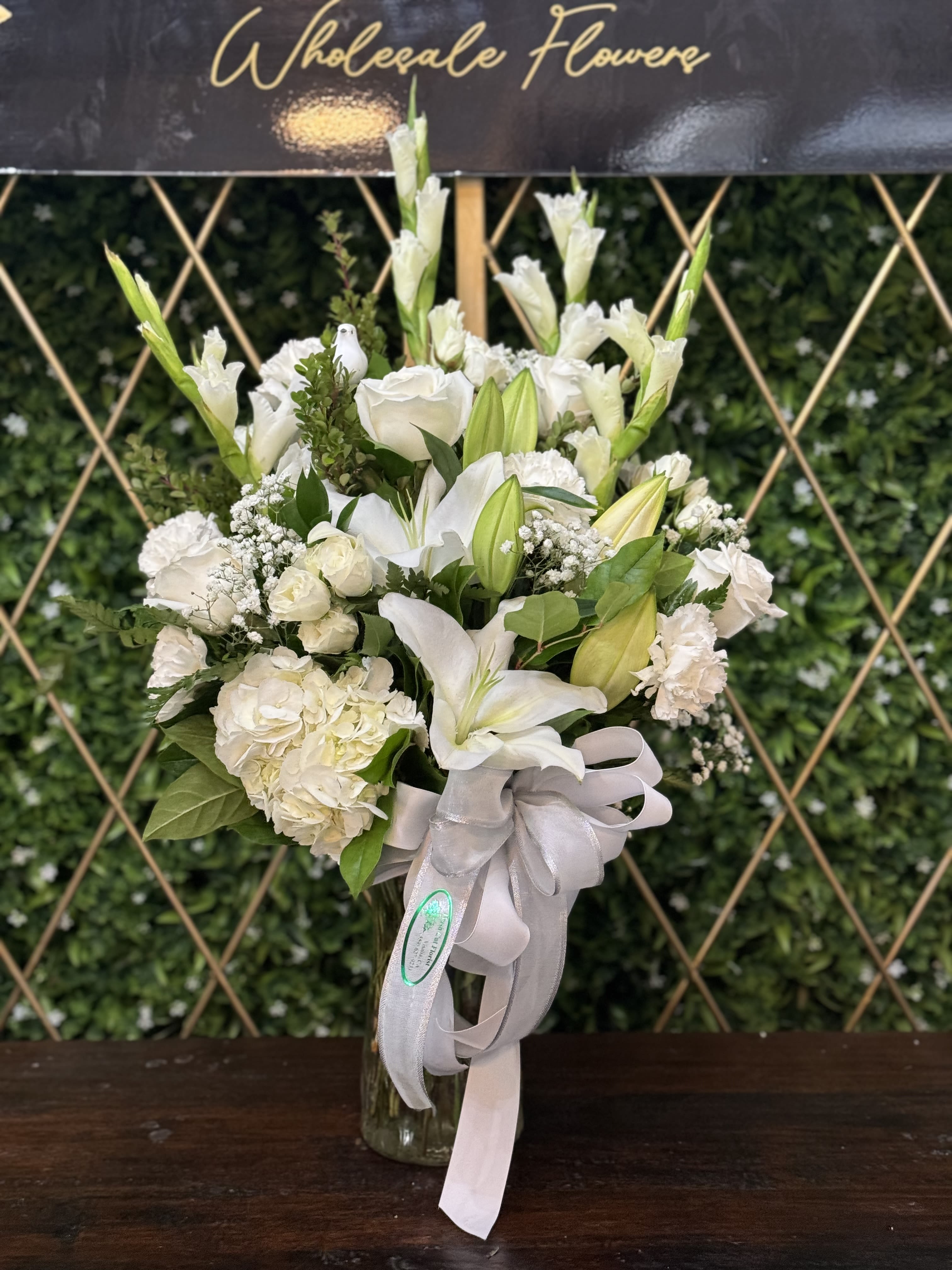 White floral bouquet in a glass vase with a pale ribbon