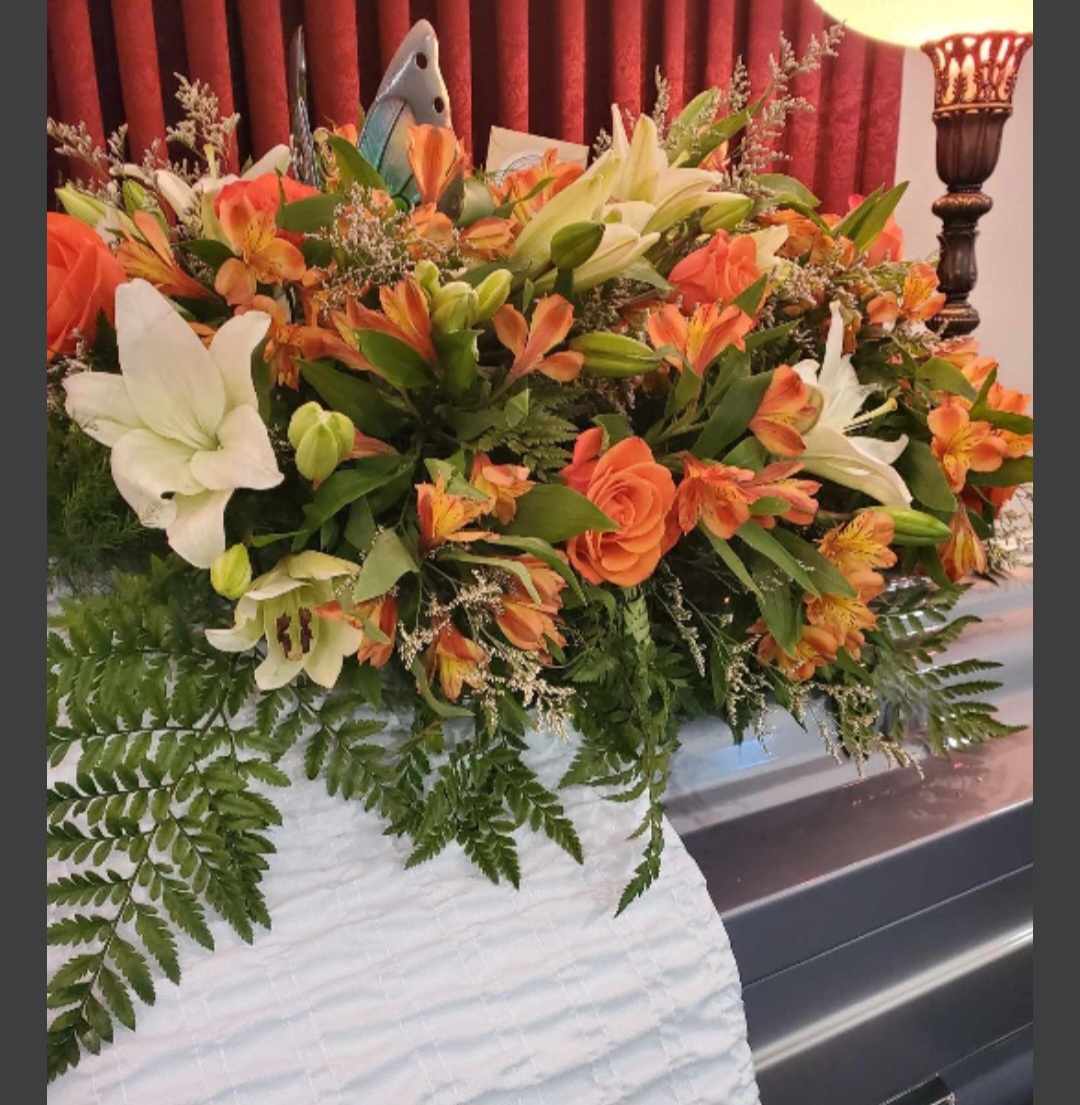 Large floral casket spray with orange and white lilies and roses