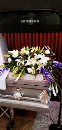 White floral arrangement with purple accents on a casket