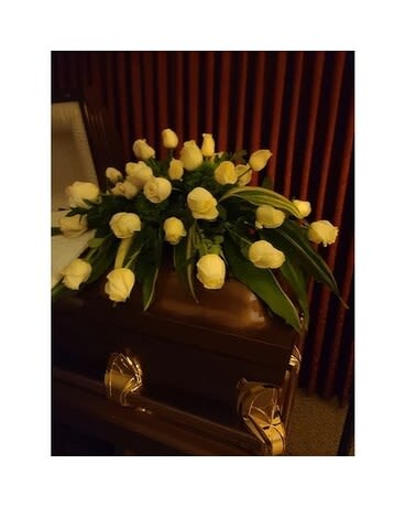 White rose arrangement on a dark casket