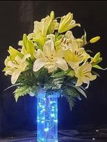 White and yellow lilies arranged in a tall blue vase