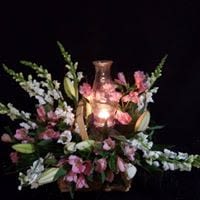 Pink and white floral arrangement around a lit glass candle holder