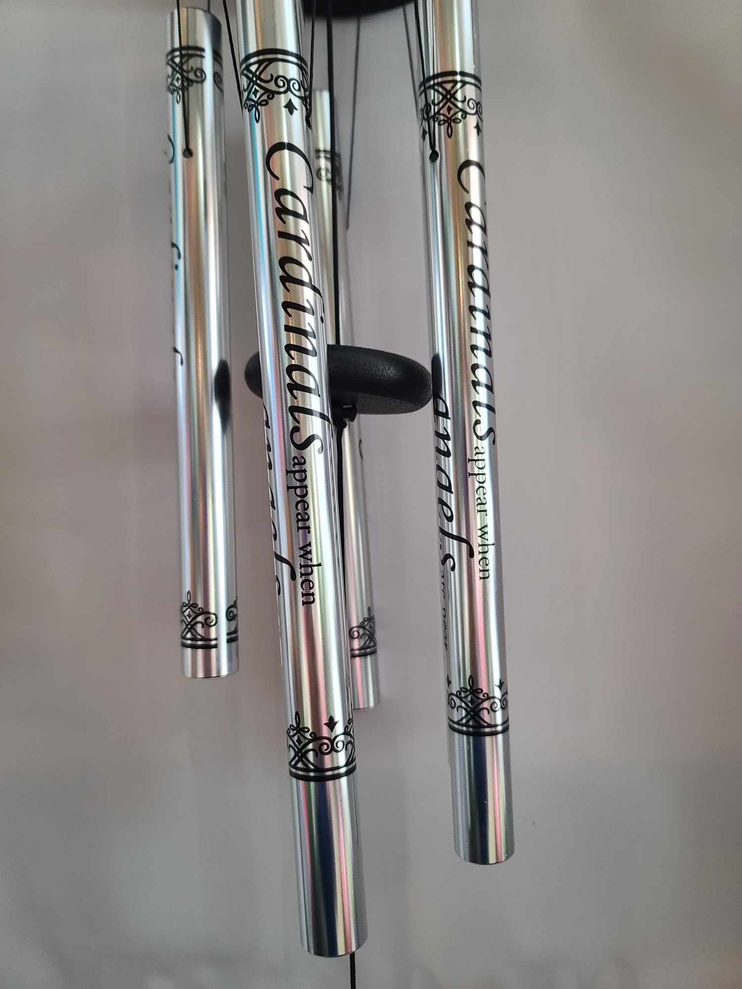 Silver wind chimes with black decorative text and scrollwork