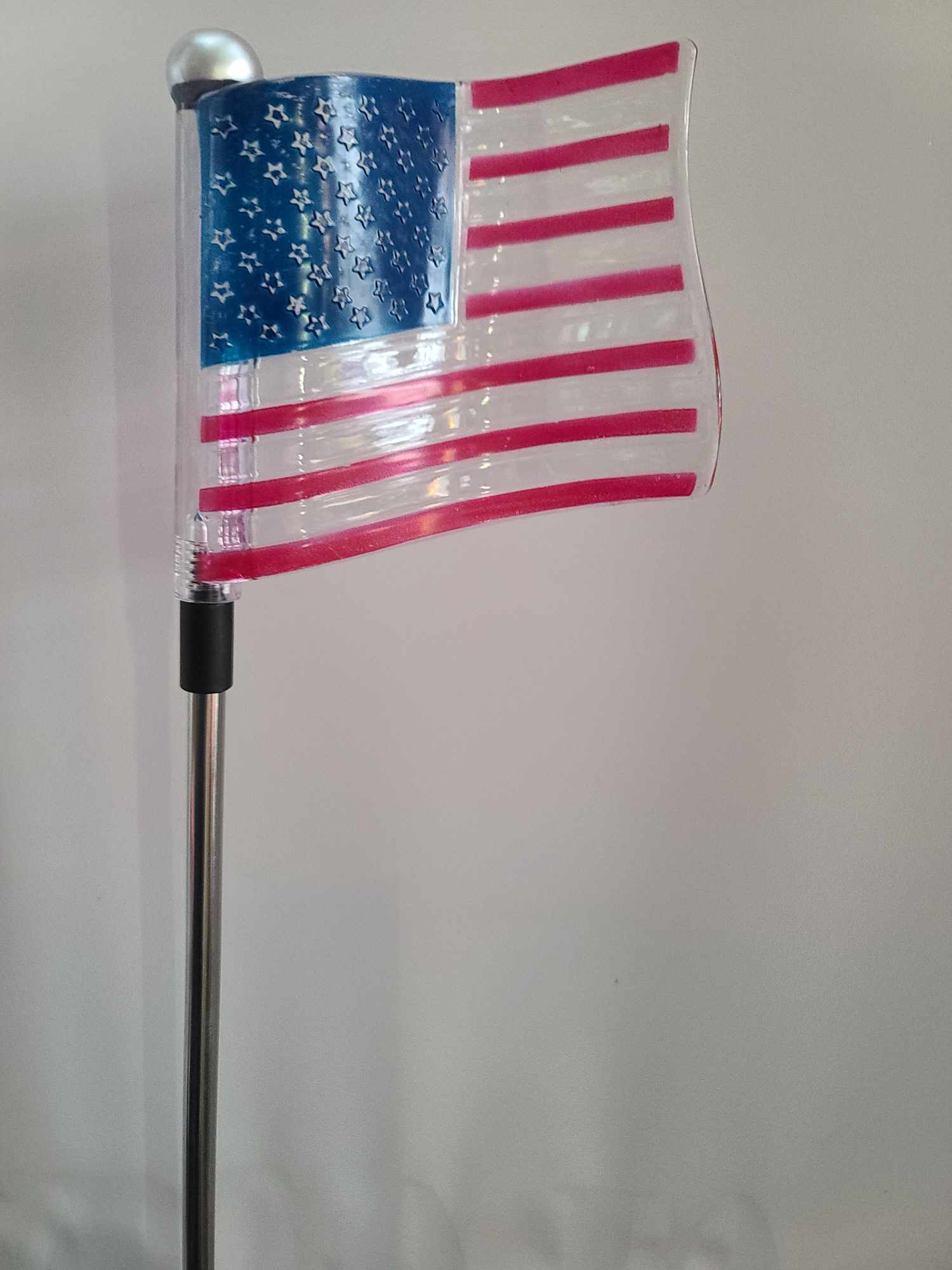 Decorative American flag on a pole against a plain wall