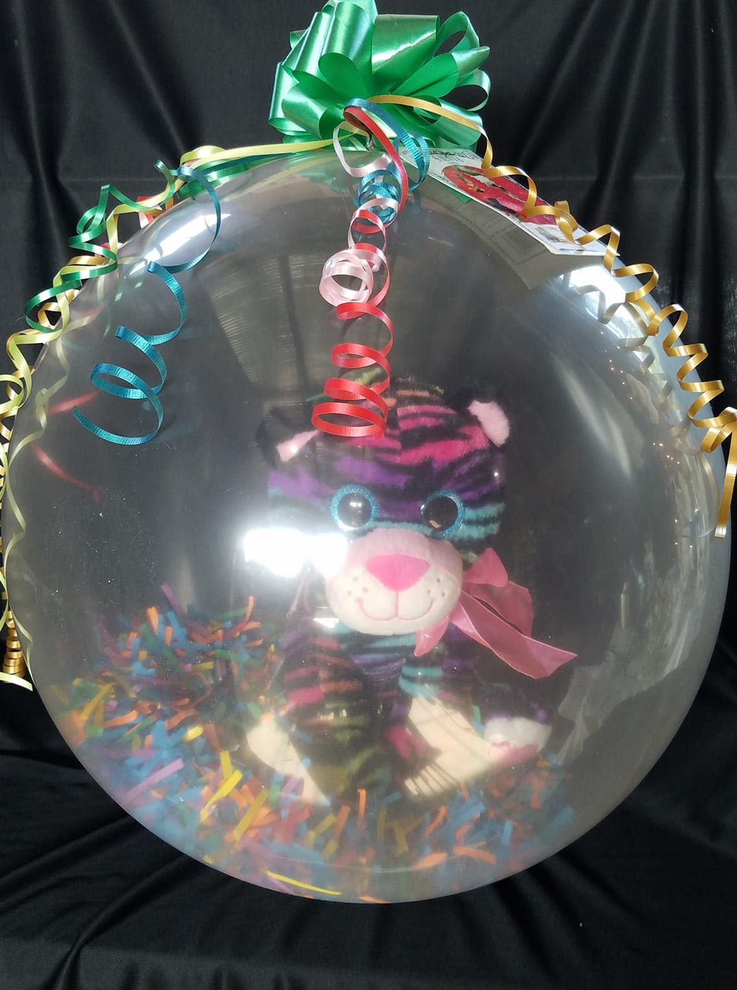 Clear balloon with a plush tiger and colorful curling ribbons