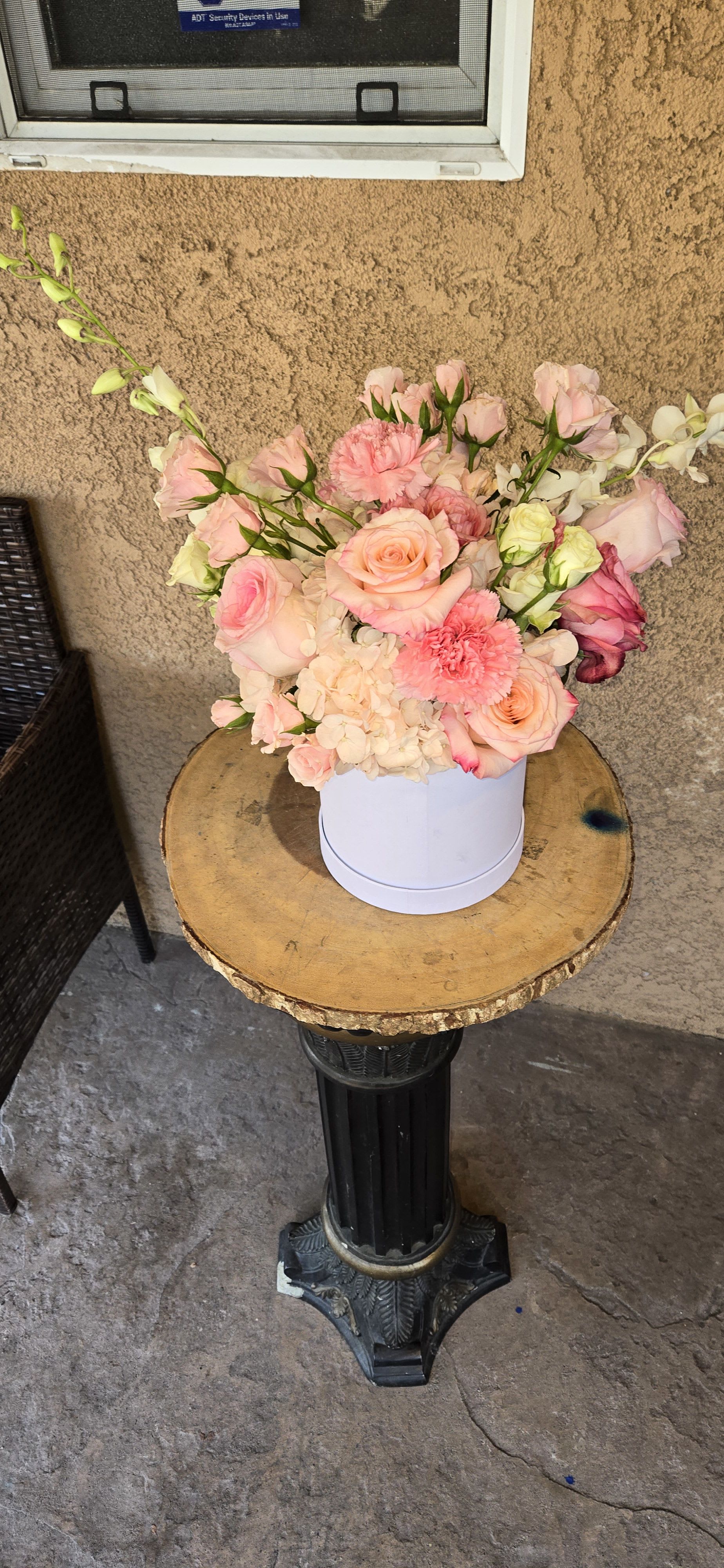 Pink and peach floral arrangement in a white round box