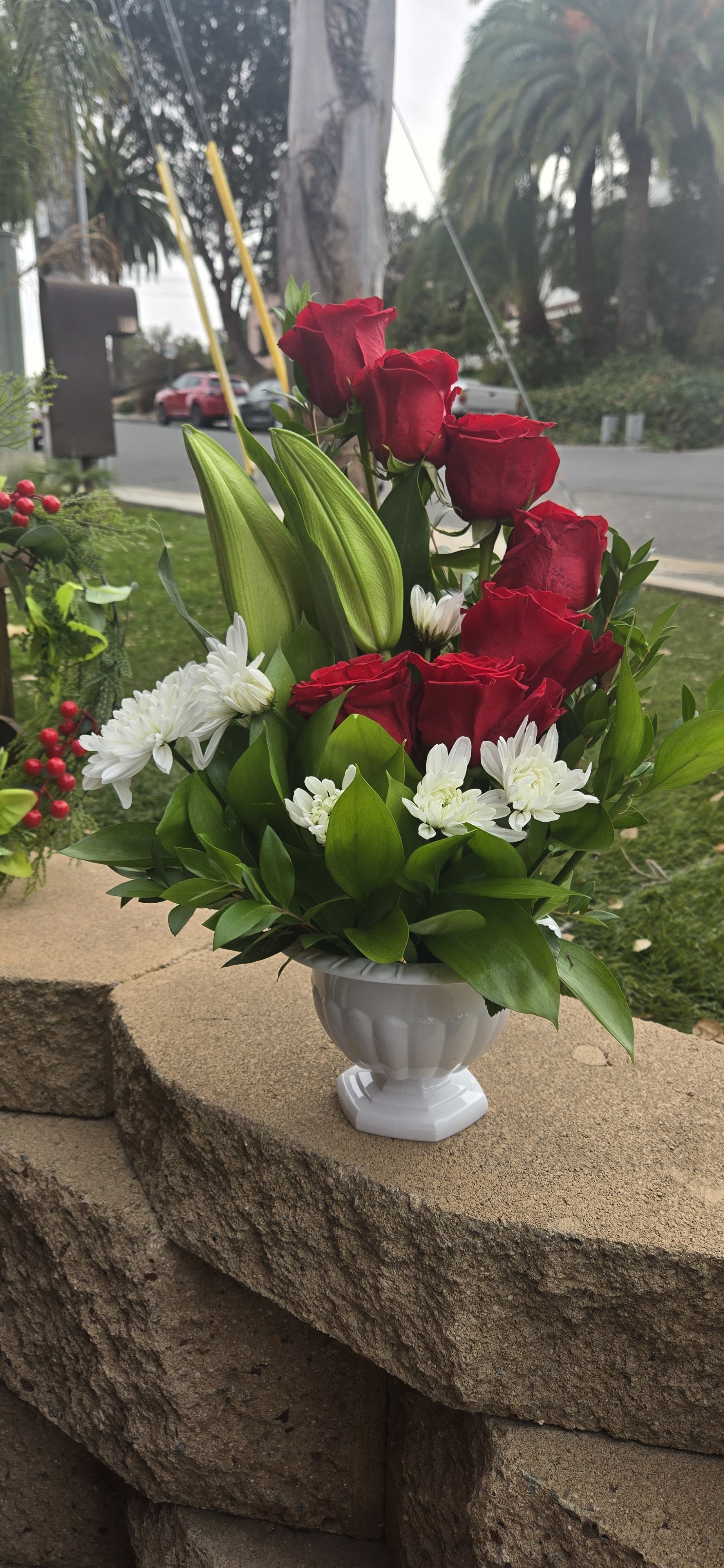 Red roses and white daisies arranged in a white vase
