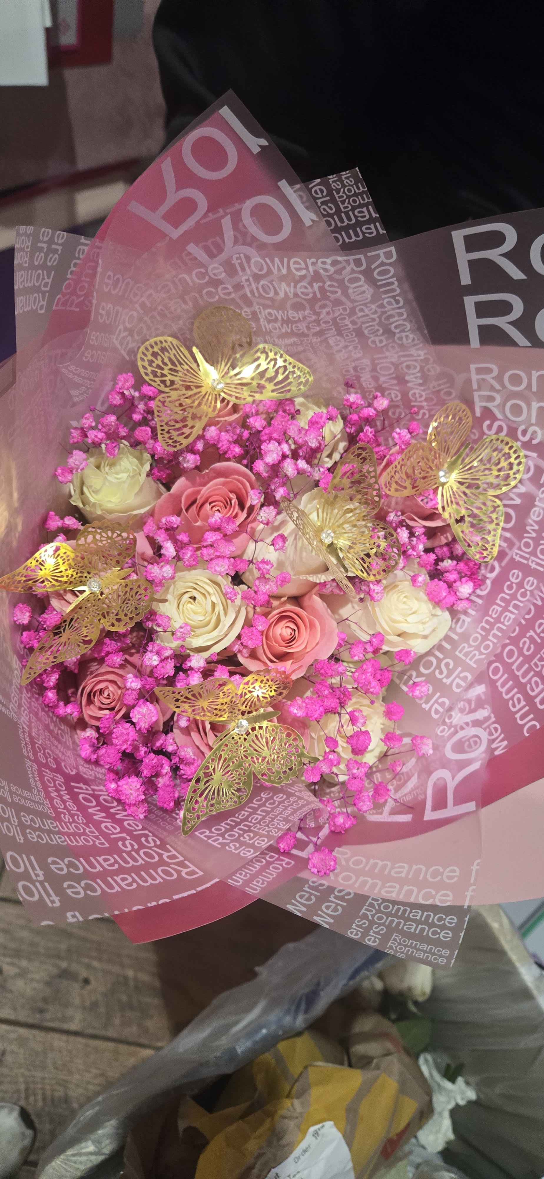 Bouquet of pink and cream roses with bright pink filler and gold butterfly decorations