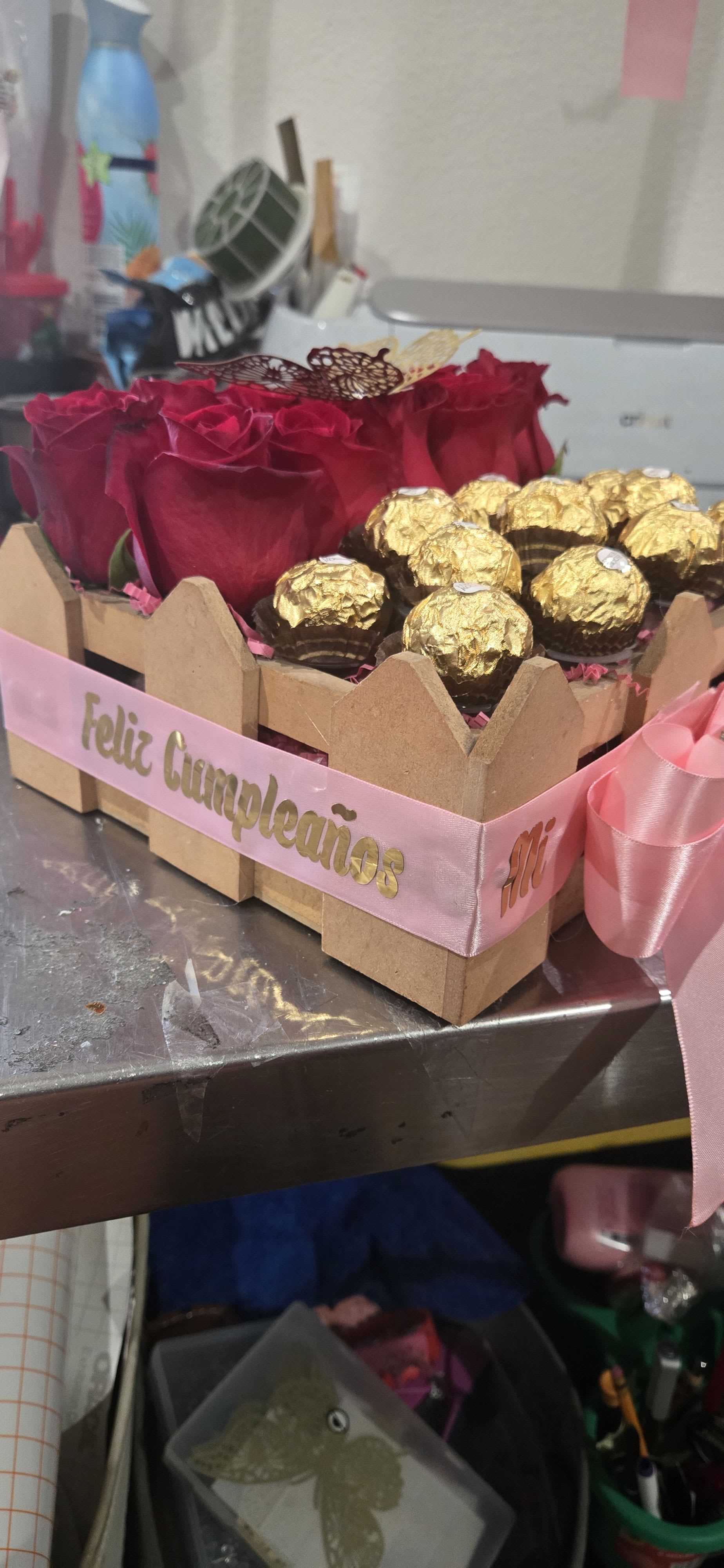 Red roses and gold-wrapped chocolates in a pink ribboned box