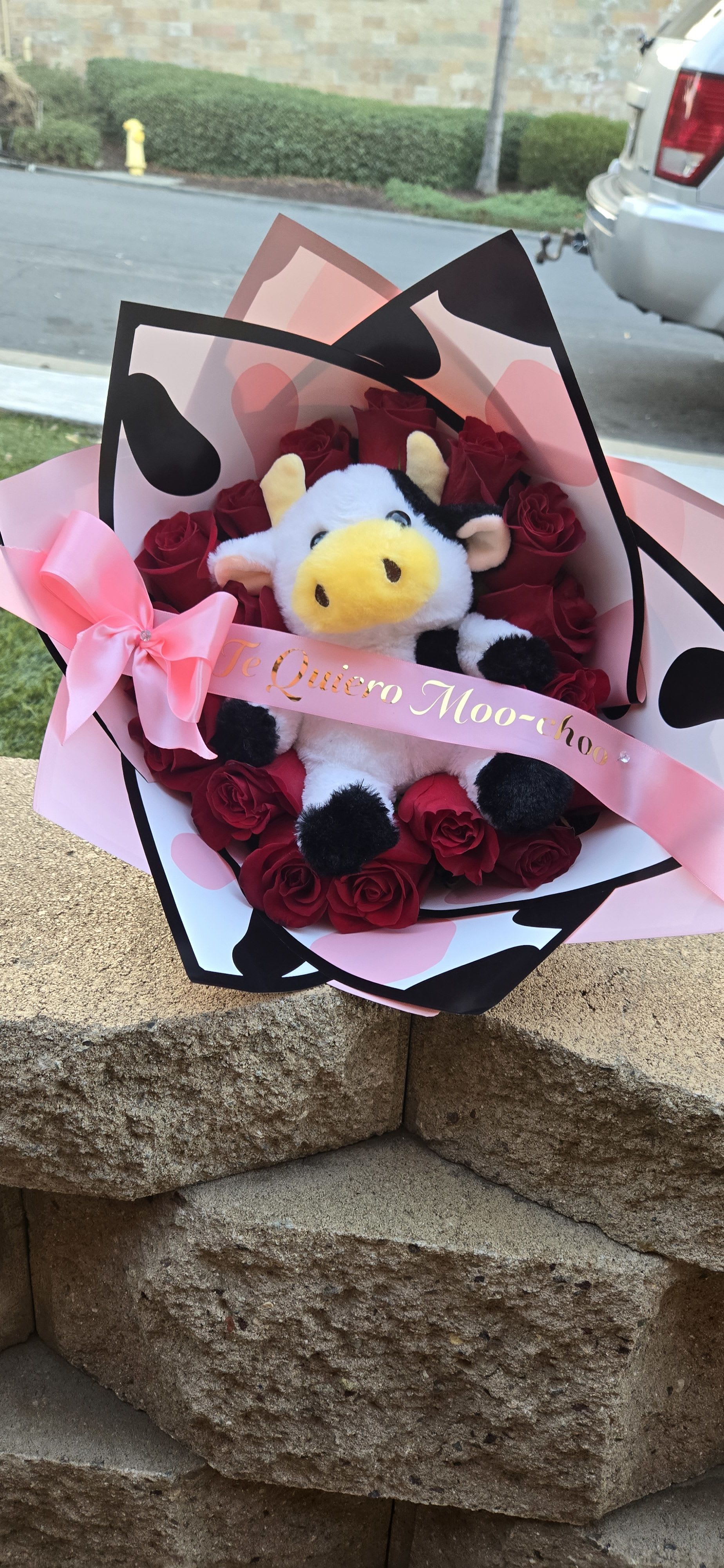 Bouquet of red roses with a plush cow and pink ribbon