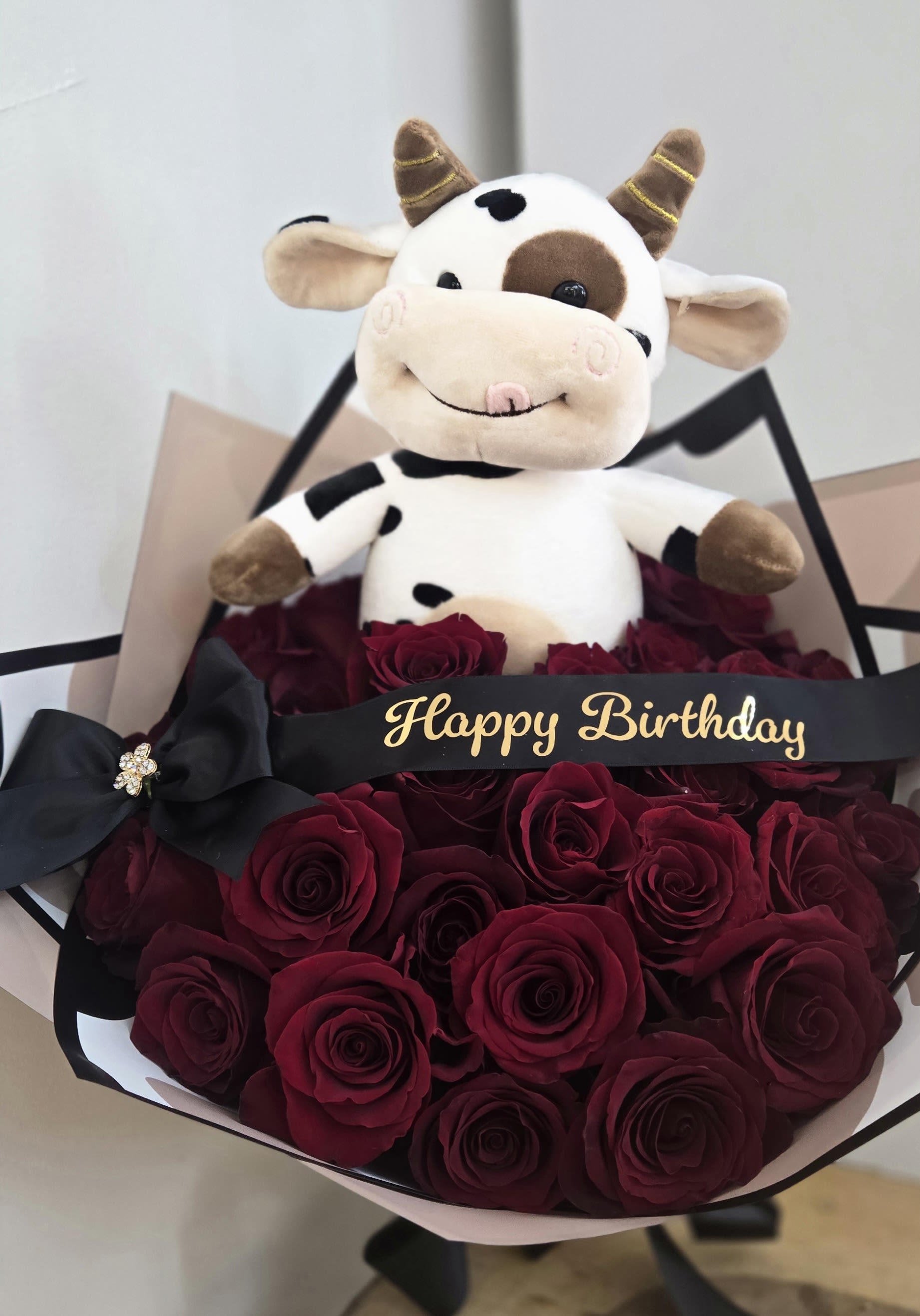 Bouquet of red roses with a plush cow and Happy Birthday ribbon