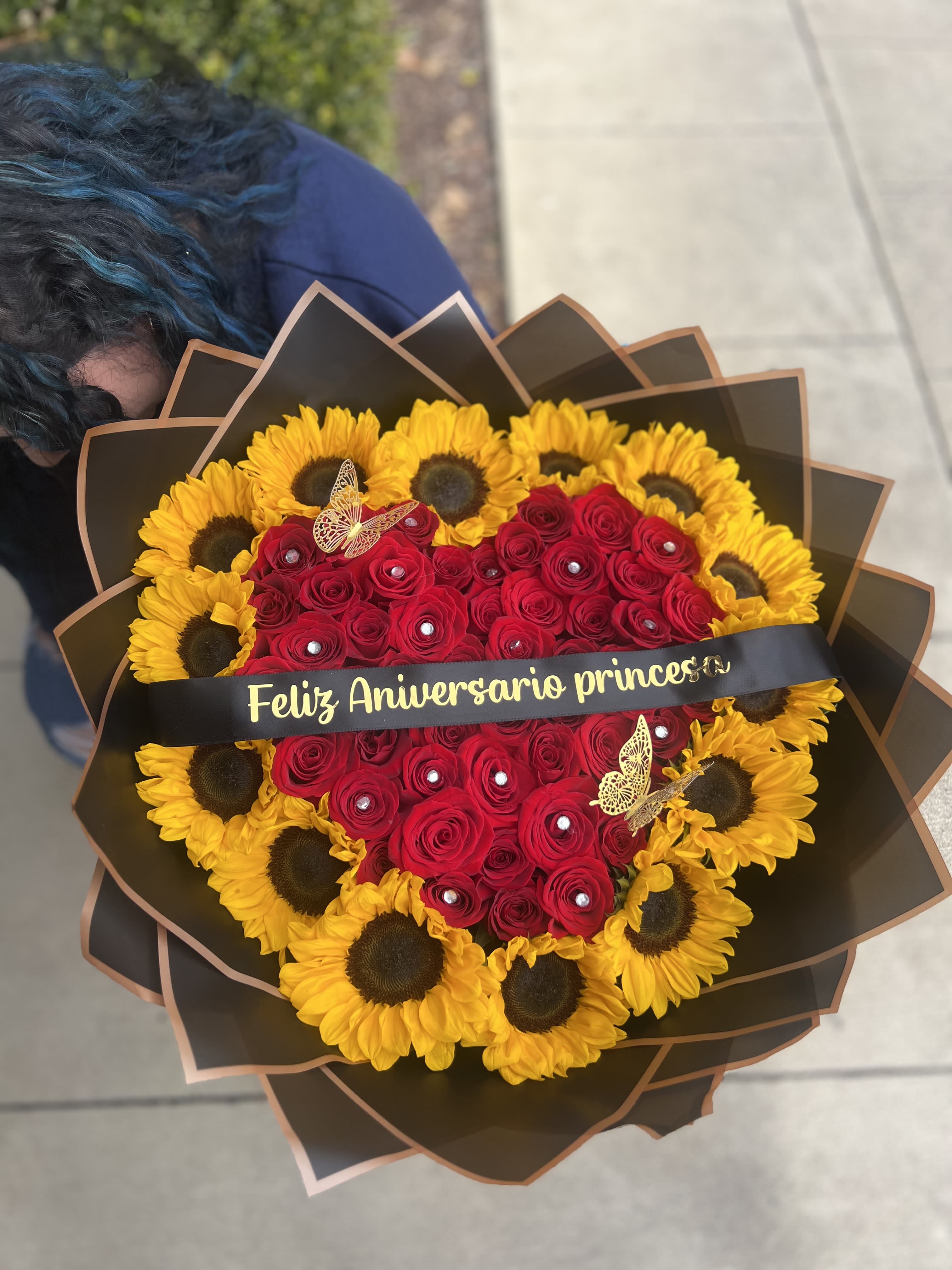 Heart-shaped bouquet of red roses and yellow sunflowers with a ribbon