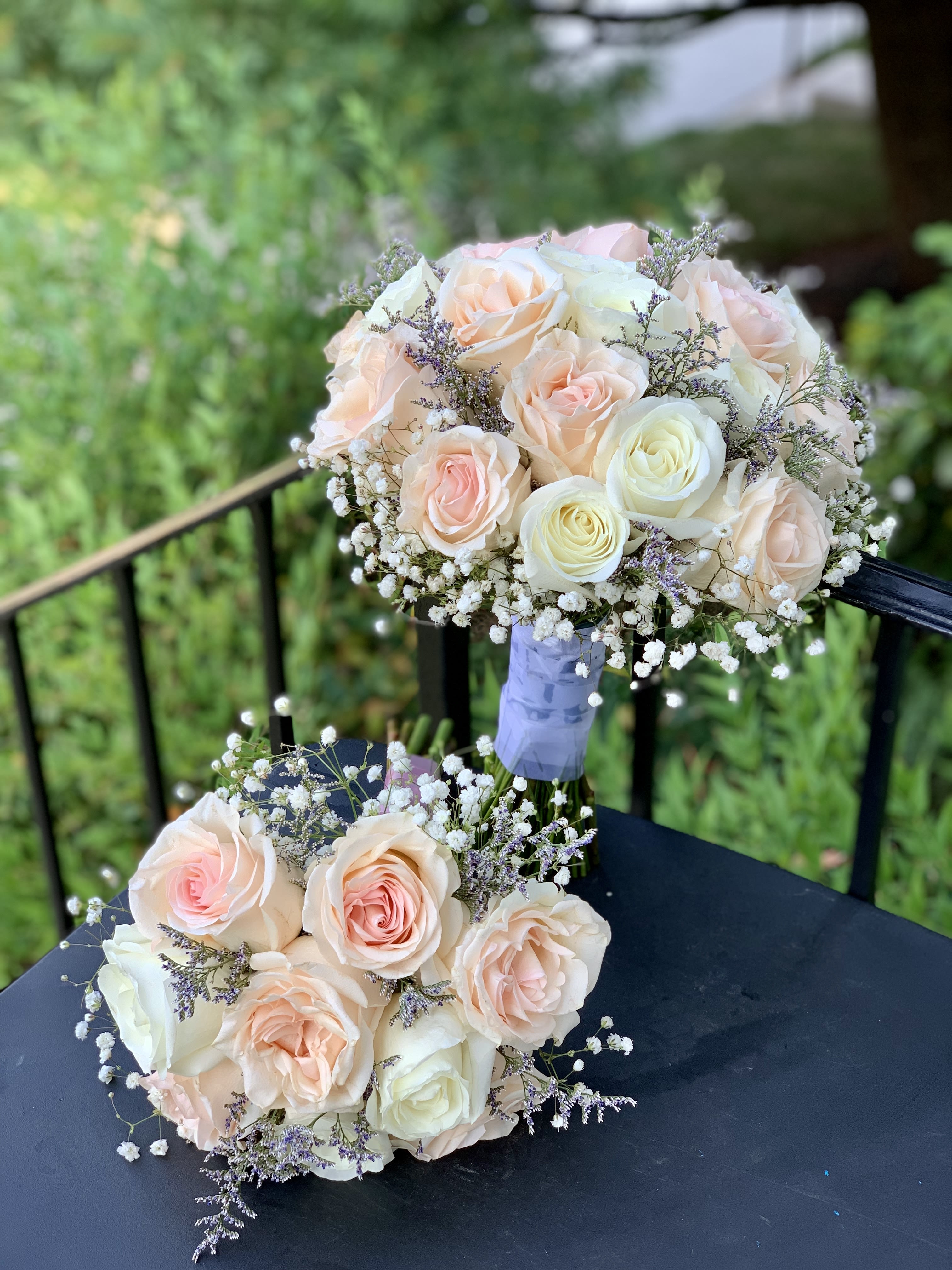 Two pastel rose bouquets with baby's breath on a dark table