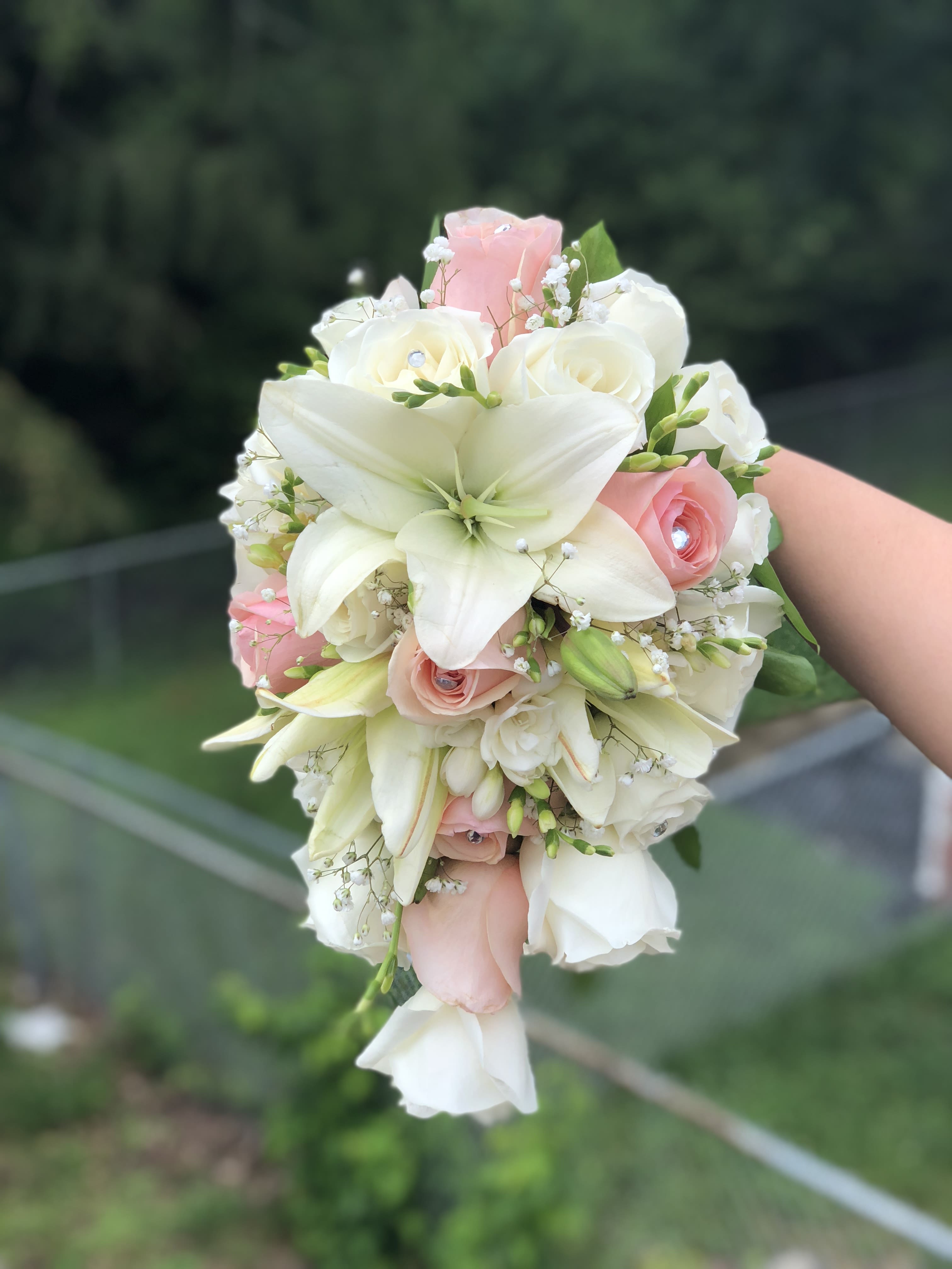 White lilies and blush roses in a hand-held bouquet