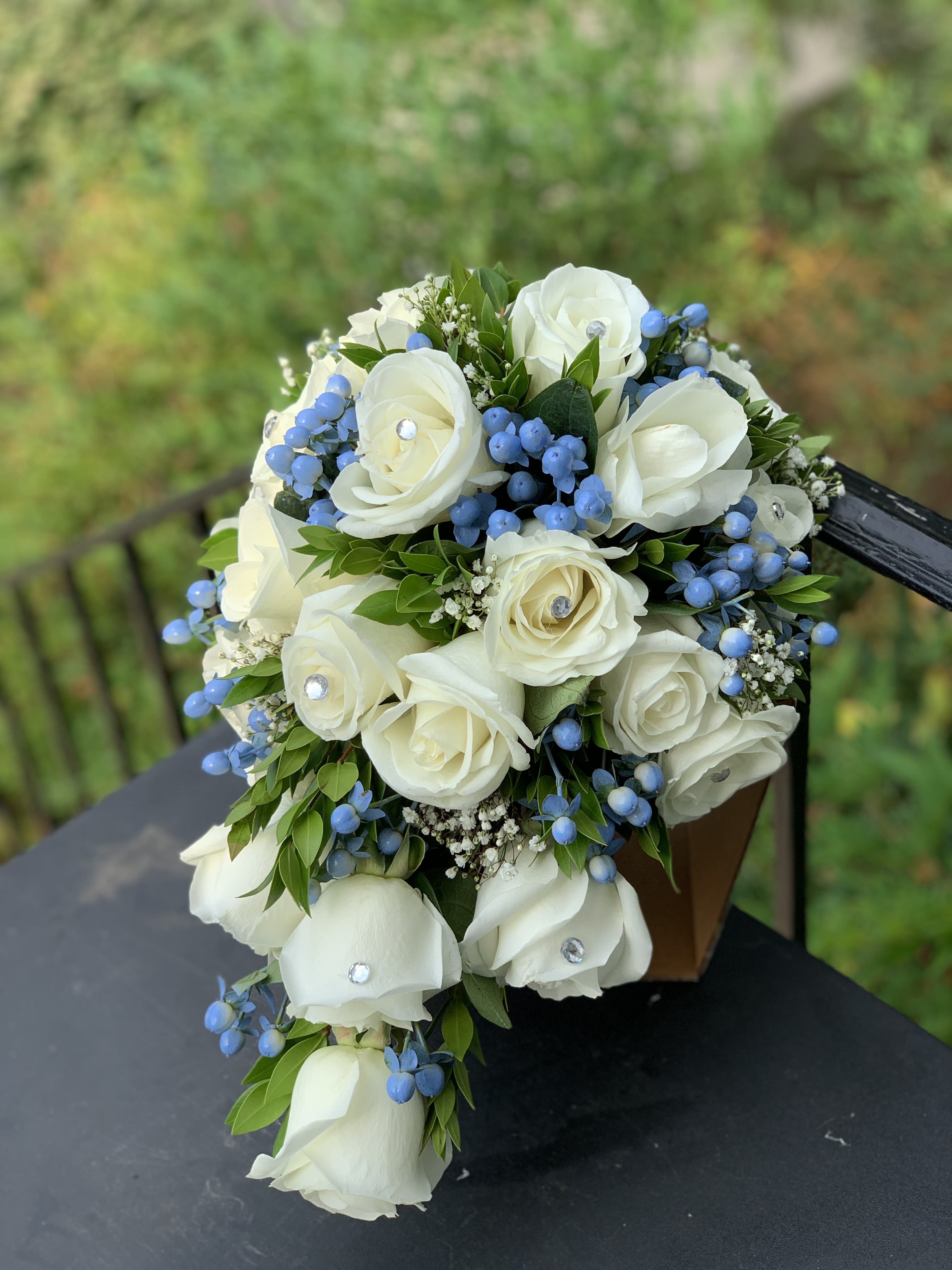 White rose bouquet with blue berries and greenery