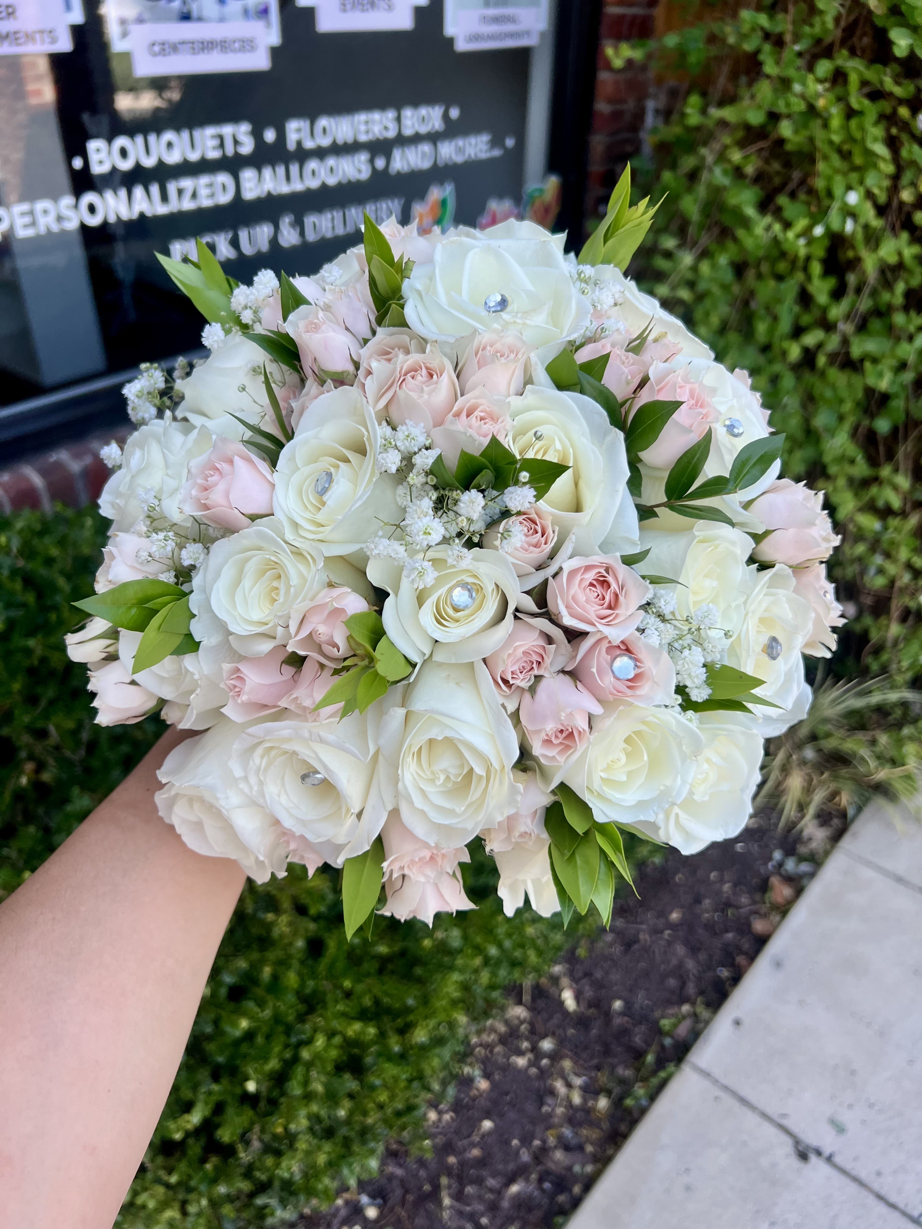 Round bouquet of white and pale pink roses with small white filler flowers