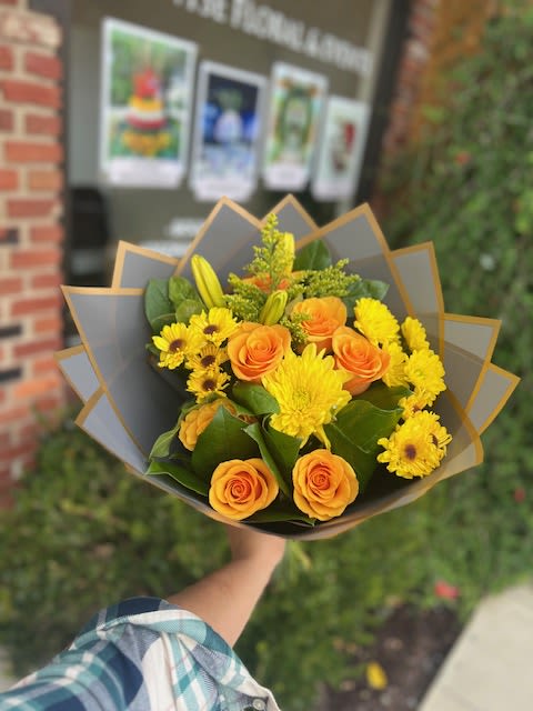 Bouquet of orange roses and yellow flowers wrapped in gray paper