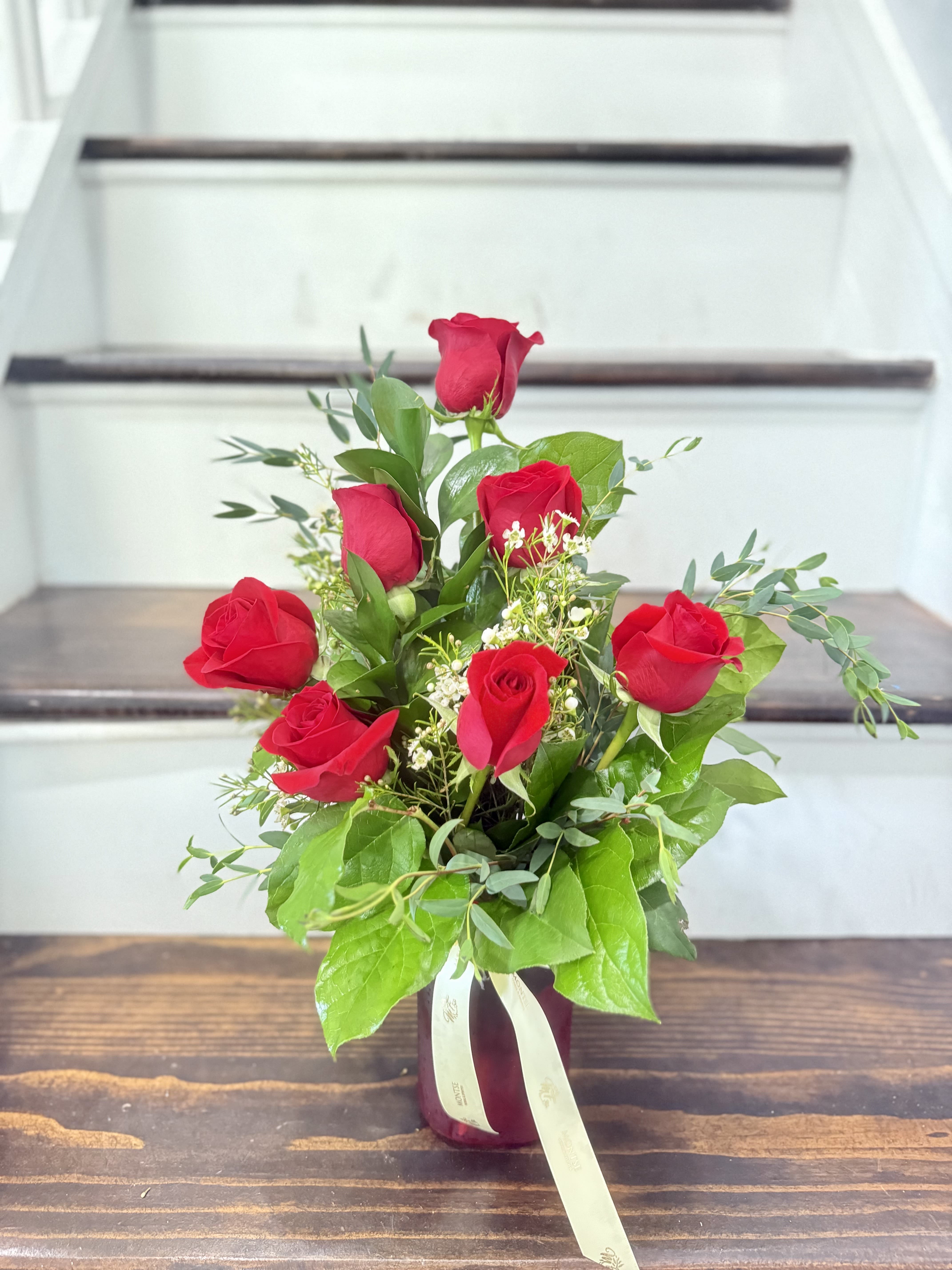 Bouquet of red roses in a burgundy vase with a ribbon