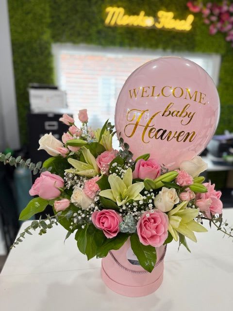 Pink and white floral arrangement with a baby shower balloon