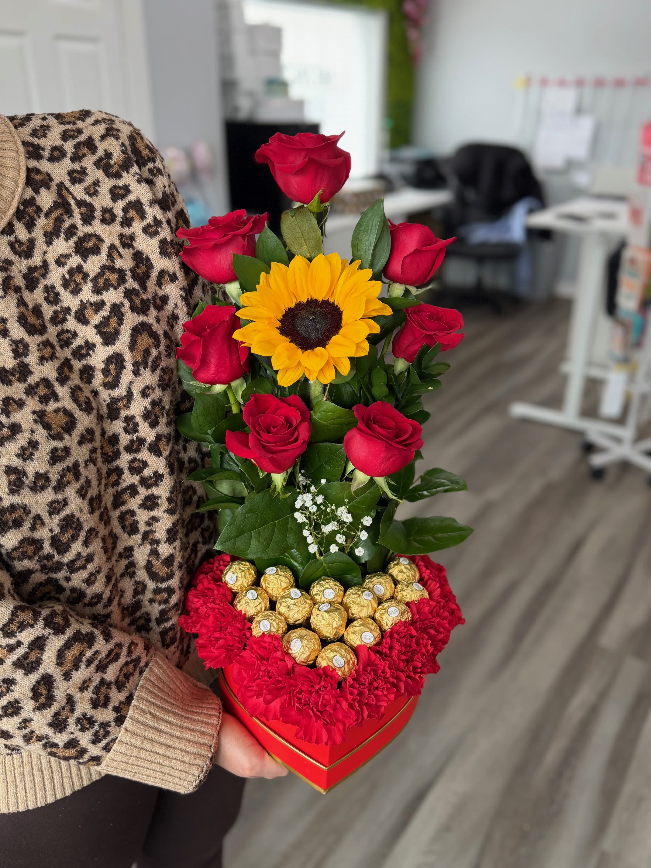 Heart-shaped box with red roses, a sunflower, and chocolates