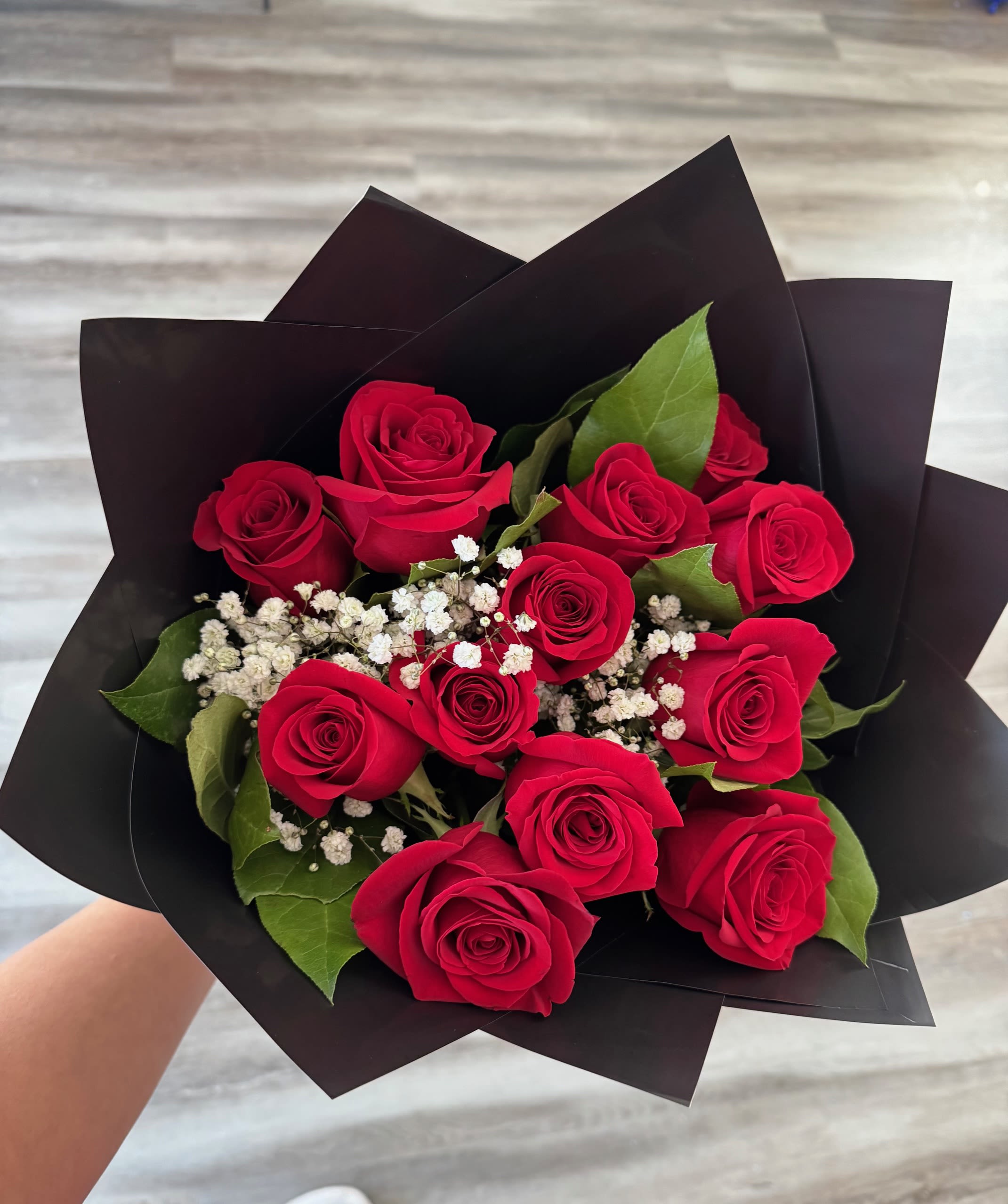 Bouquet of red roses with white baby's breath in black wrap