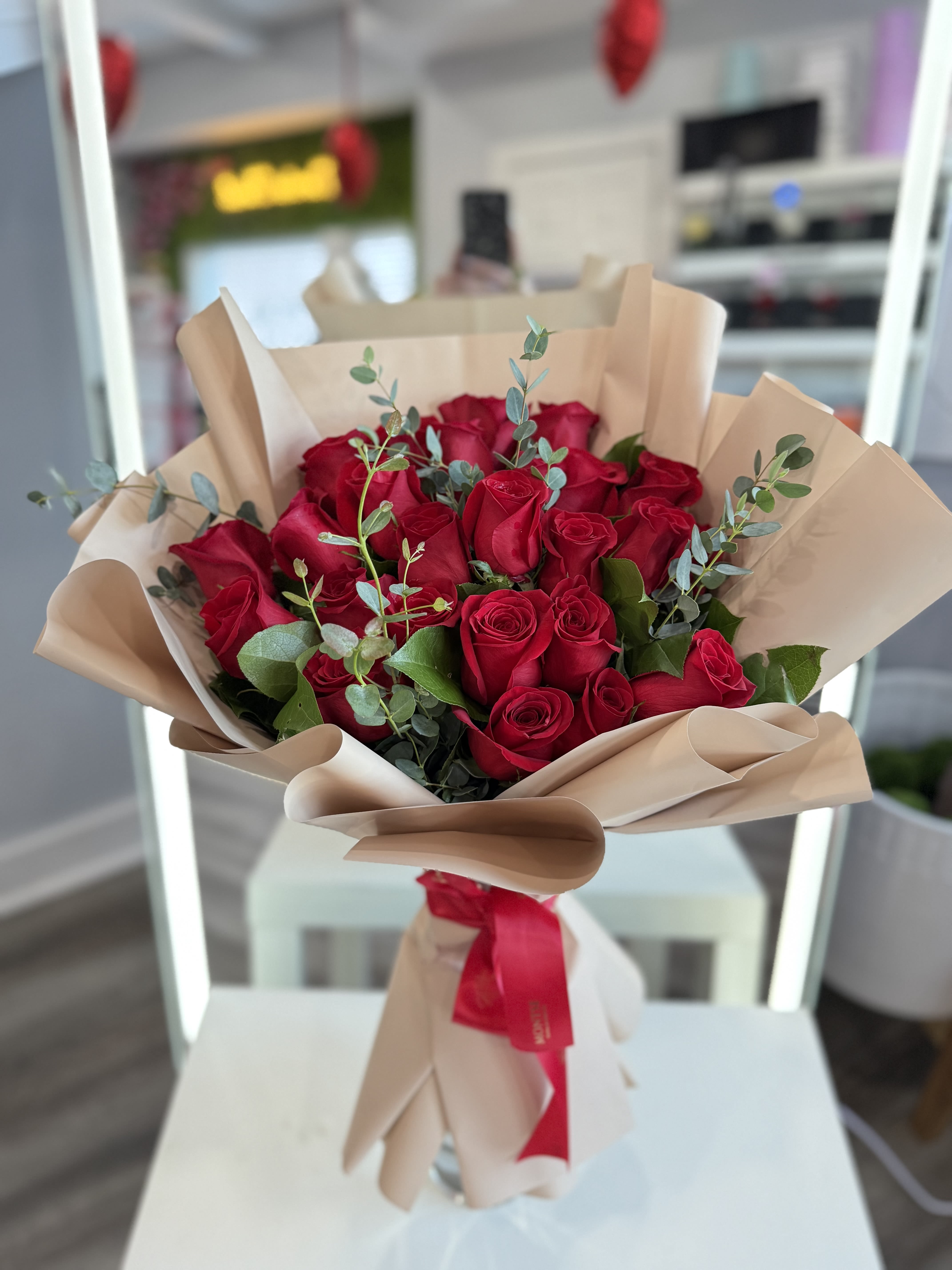 Bouquet of red roses wrapped in beige paper with a red ribbon