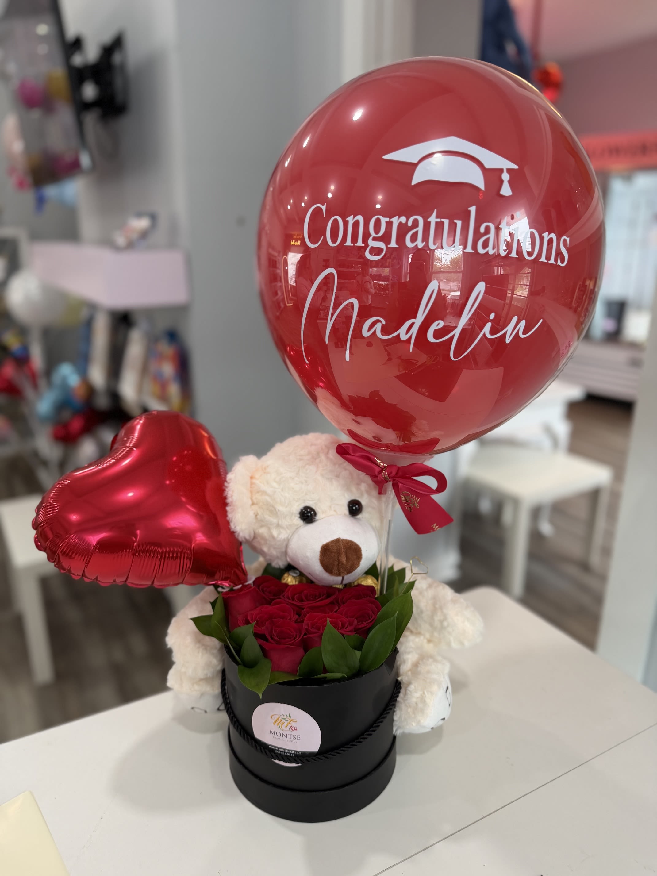 The Grad box  - Black round box with a cluster of red roses, teddy bear, graduation custom  balloon and heart-shaped foil balloon.