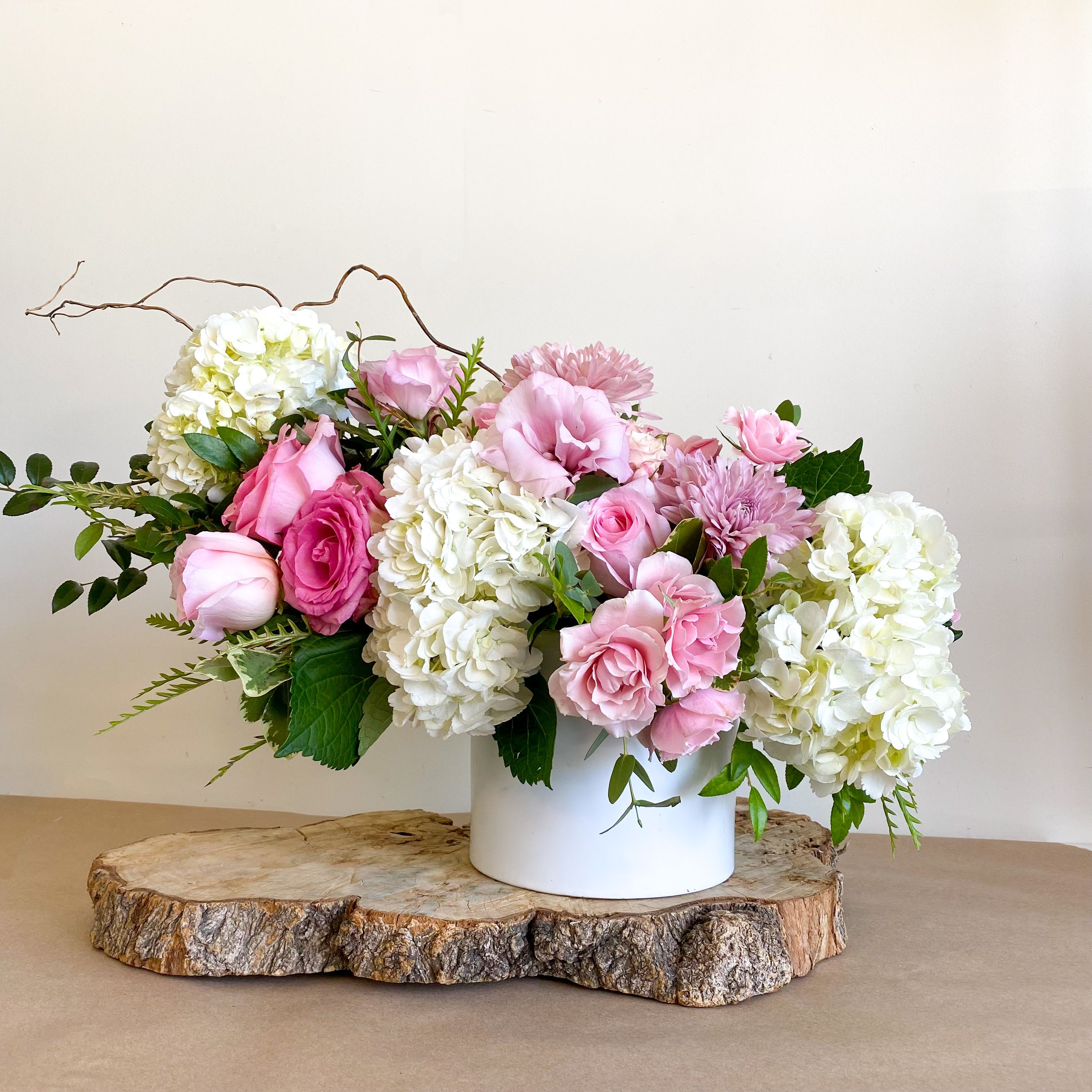 Pink roses and white hydrangeas arranged in a white vase