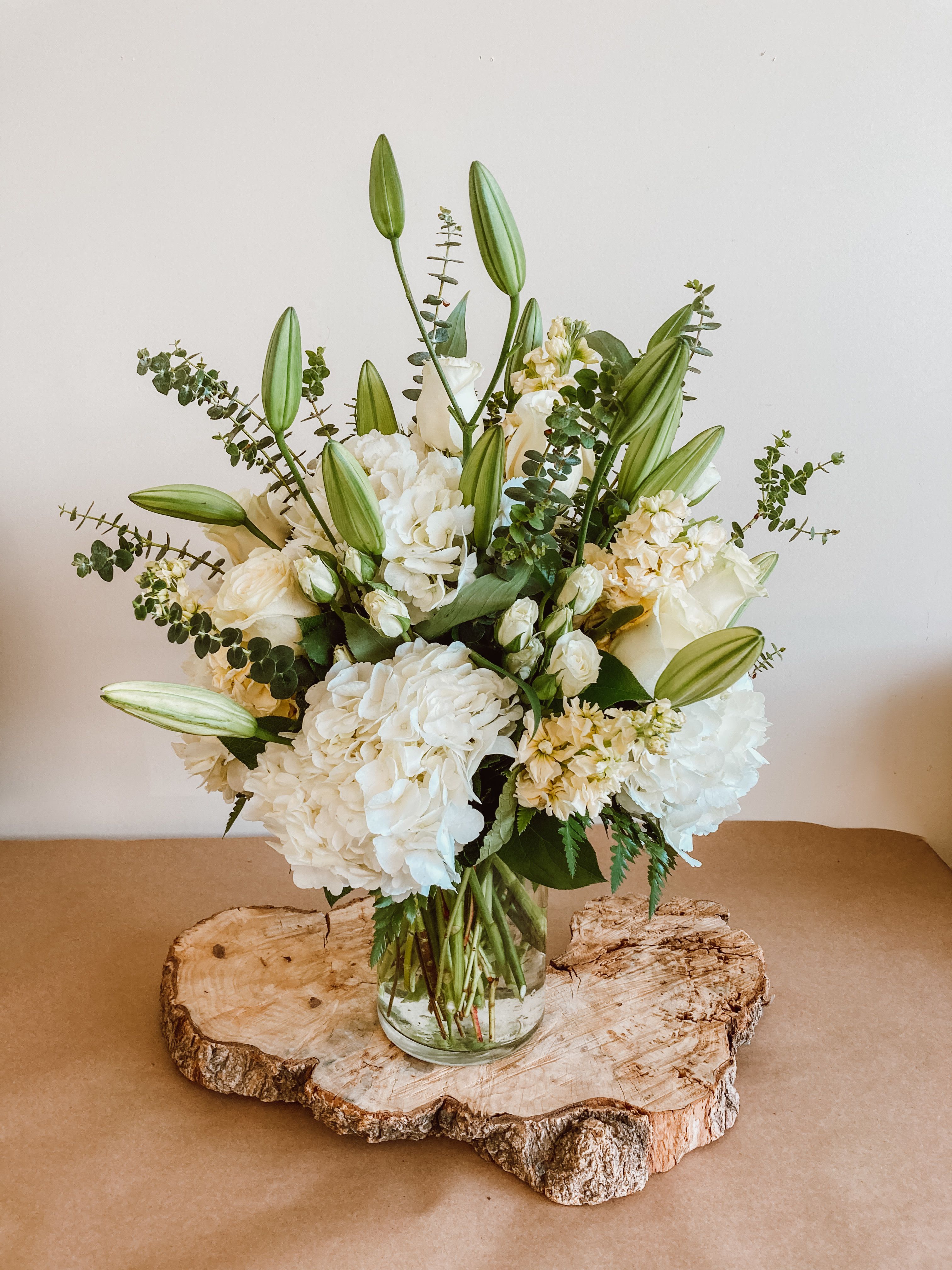 White floral arrangement in a glass vase with tall lily buds