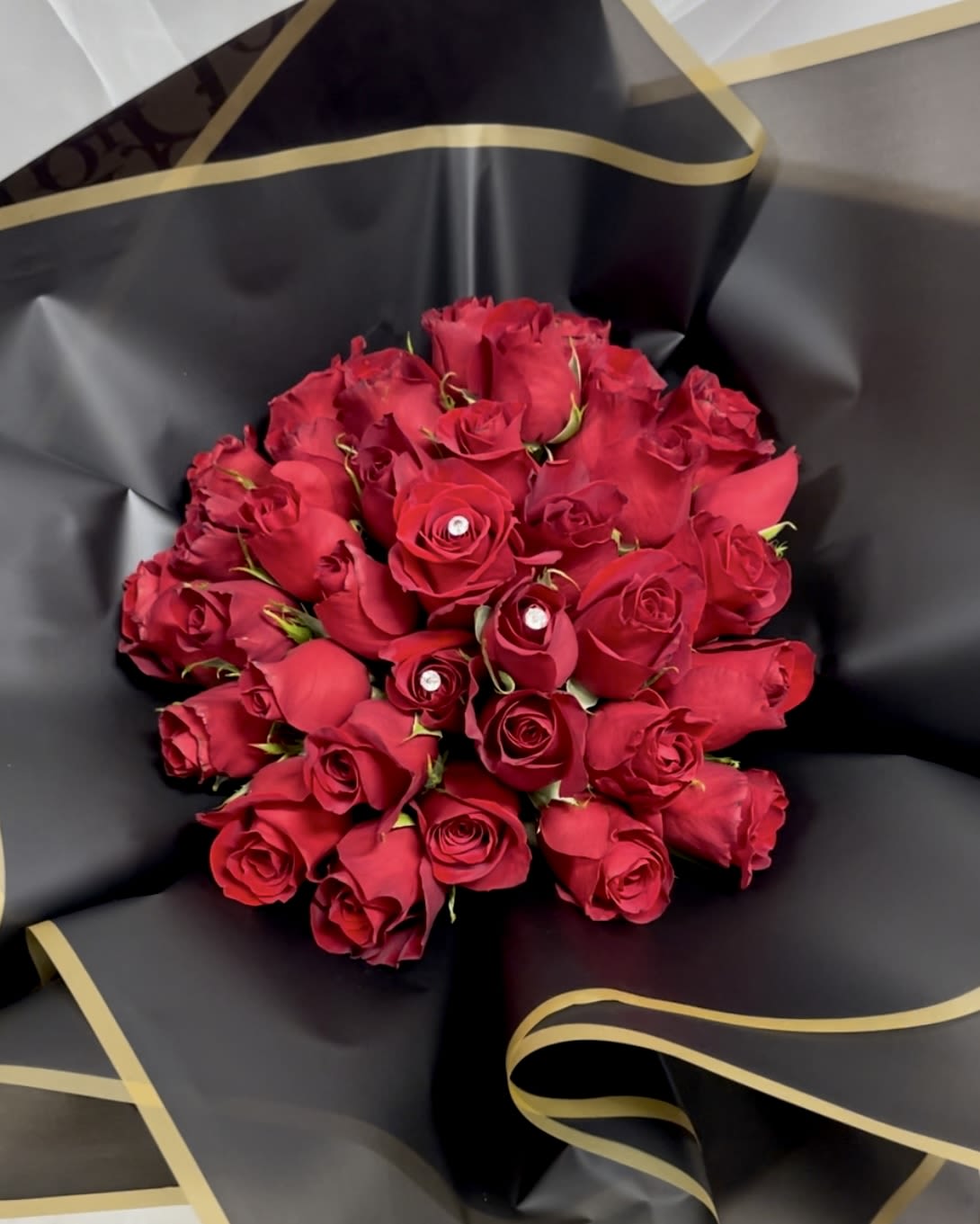 Bouquet of red roses wrapped in black paper with gold trim