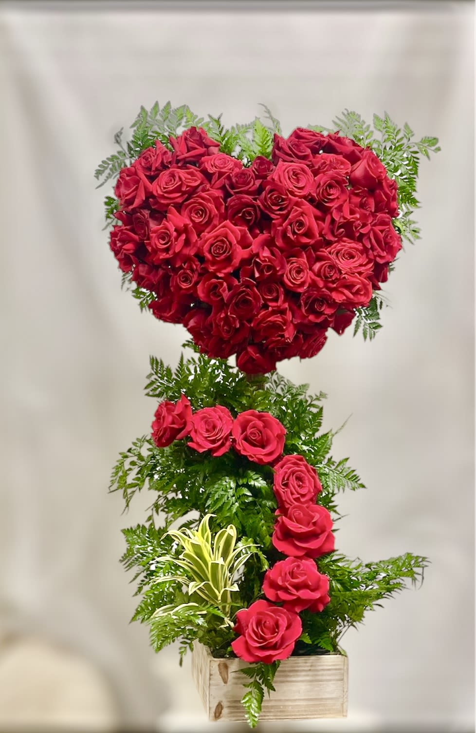 Heart-shaped red rose arrangement in a wooden box