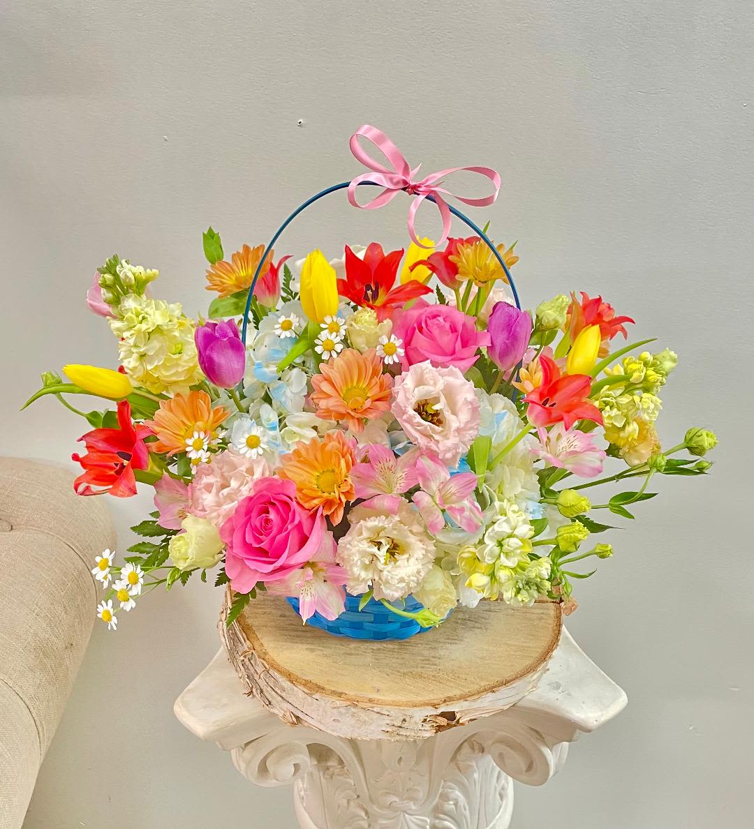 Colorful mixed flower basket with a pink ribbon handle